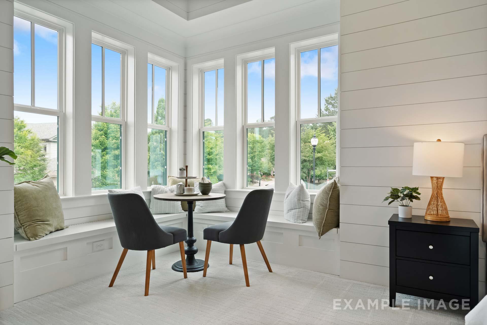 Bright bay window nook in Manor Estates home, Marietta GA with white shiplap walls, round table, chairs, pillows, and plants by Davidson Homes