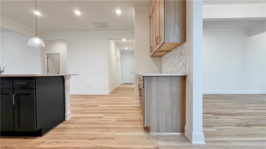 Modern open-concept kitchen in The Glenwood A at Wehunt Meadows, Hoschton, GA, featuring a dark island and wood cabinetry.