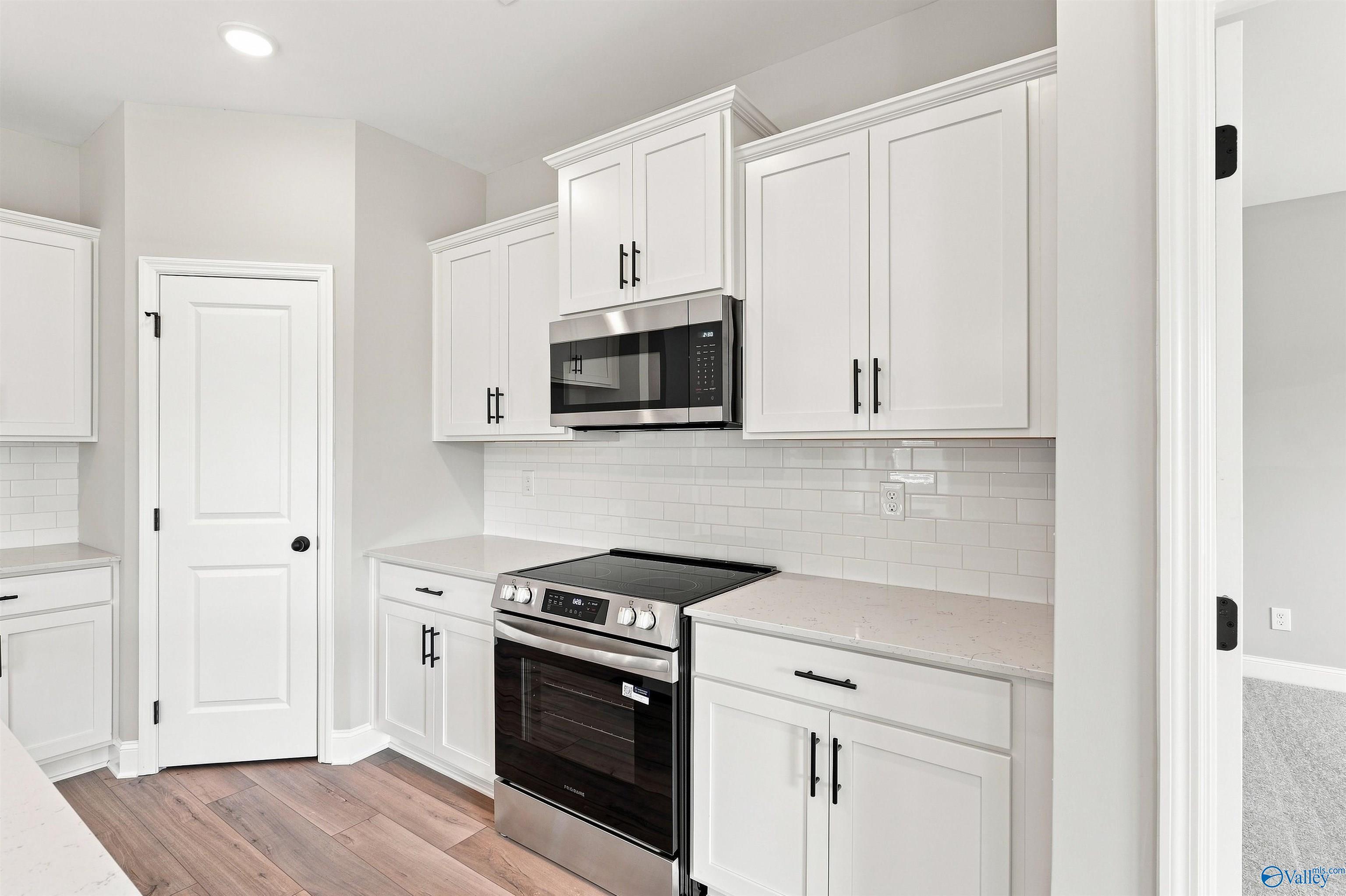 Modern kitchen with white shaker cabinets, stainless appliances, and quartz countertops in Davidson Homes Franklin C, Toney AL