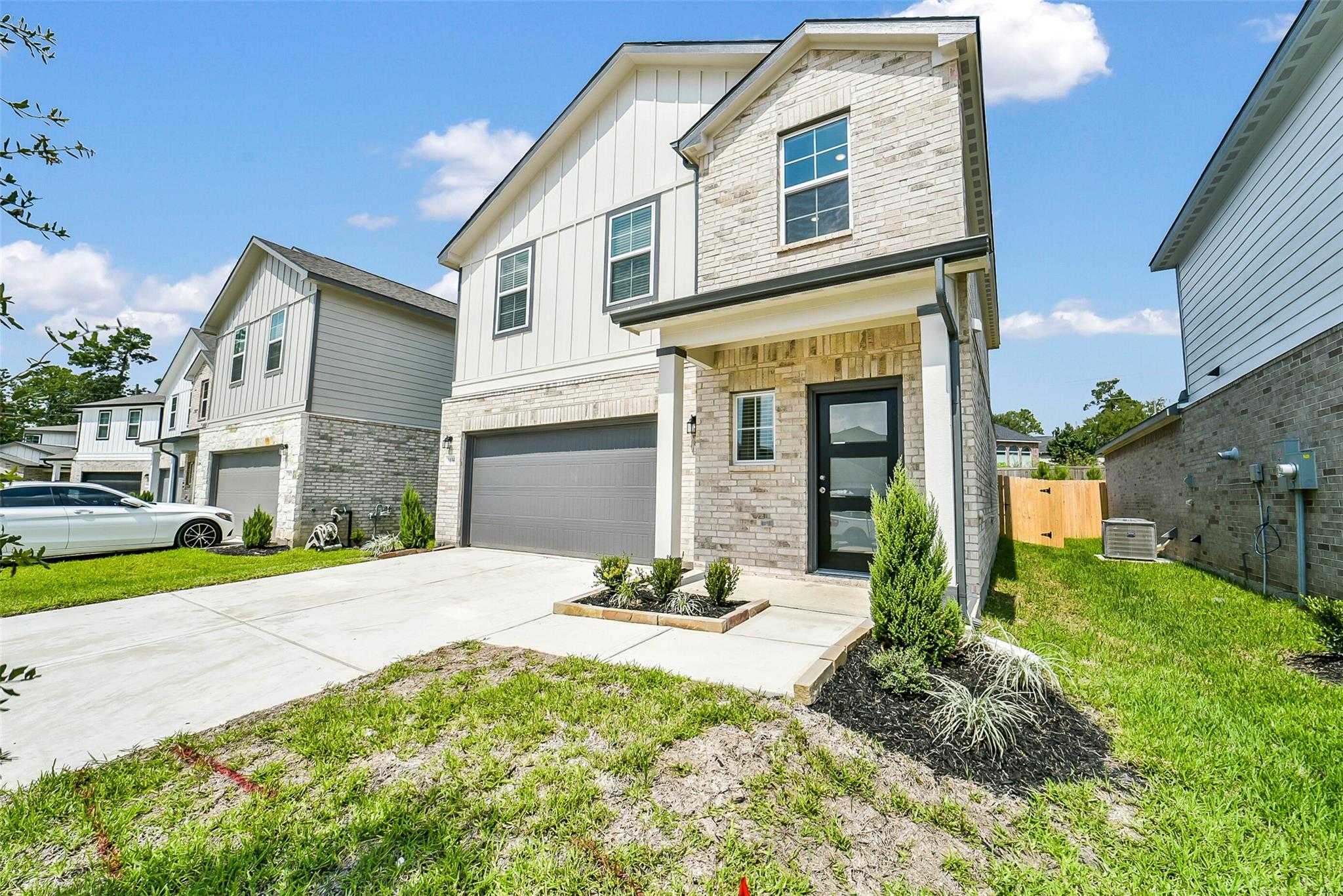 Modern two-story Davidson Homes Trinity F exterior with brick accents, two-car garage, driveway, and landscaped yard in Magnolia, Texas