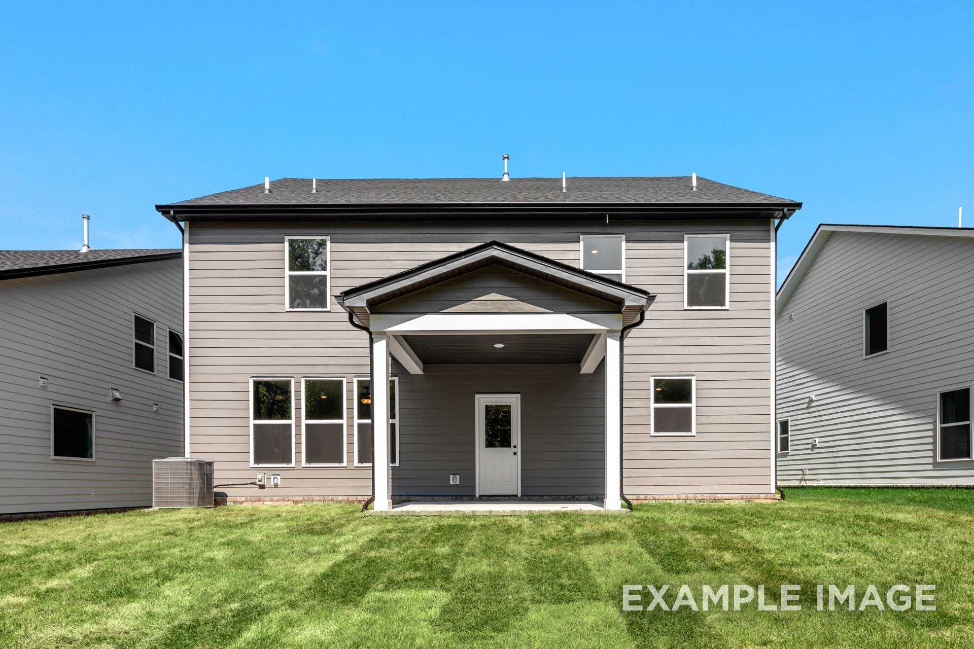 Rear elevation of The Henry B 2-story home with covered porch, gray siding, windows, and lush green backyard in Mt. Juliet