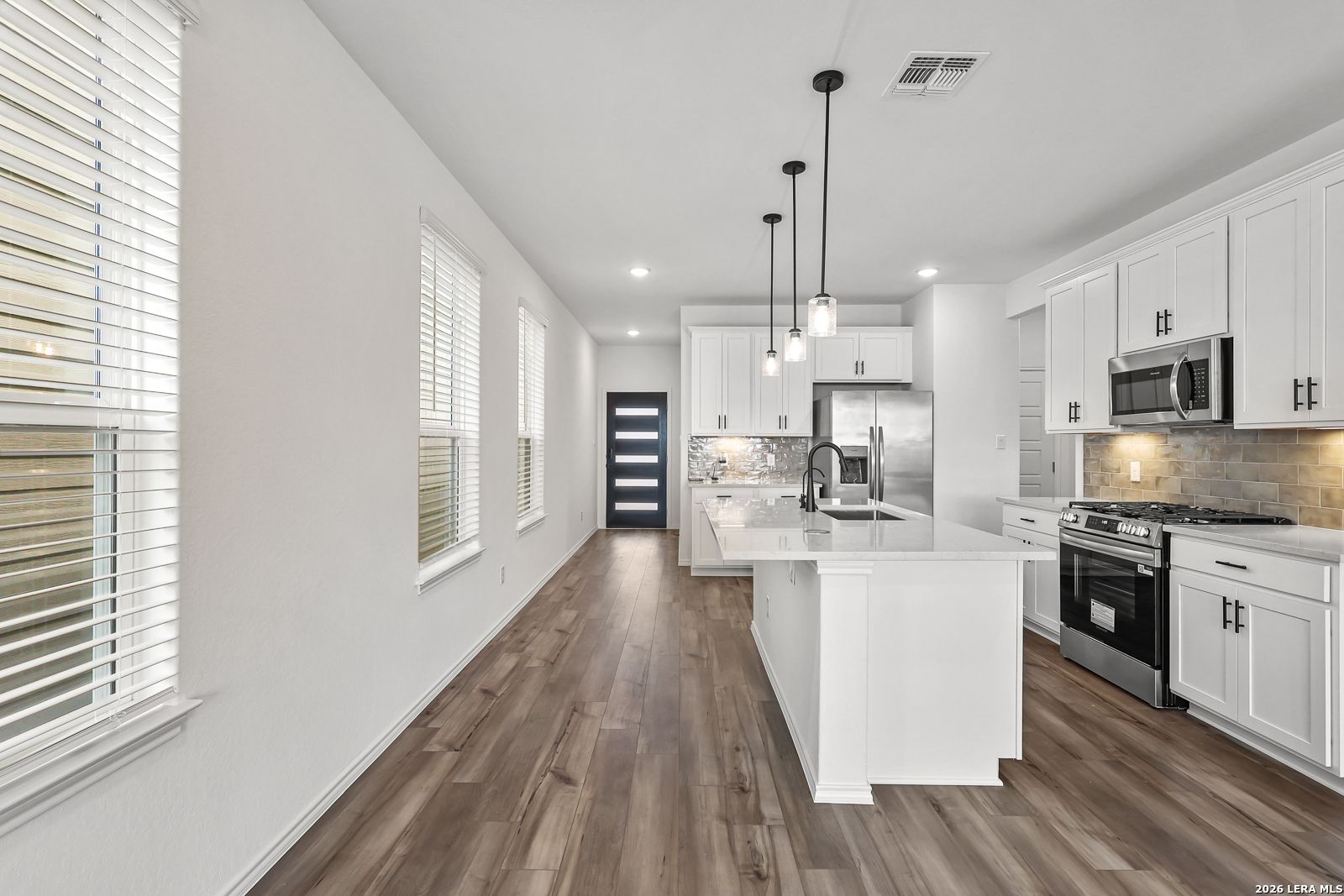 Modern kitchen with white cabinetry and island in The Gillian C floor plan at Meadows at Oak Creek, San Antonio, Texas.