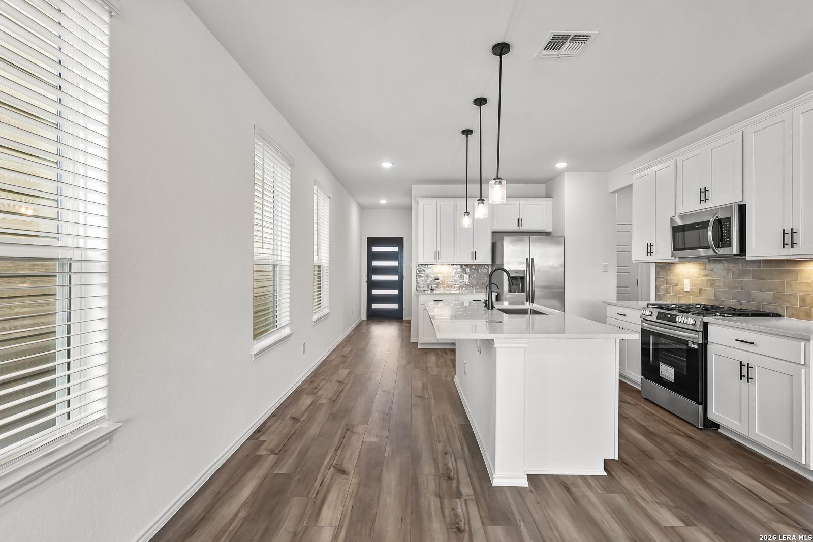 Modern kitchen with white cabinetry and island in The Gillian C floor plan at Meadows at Oak Creek, San Antonio, Texas.