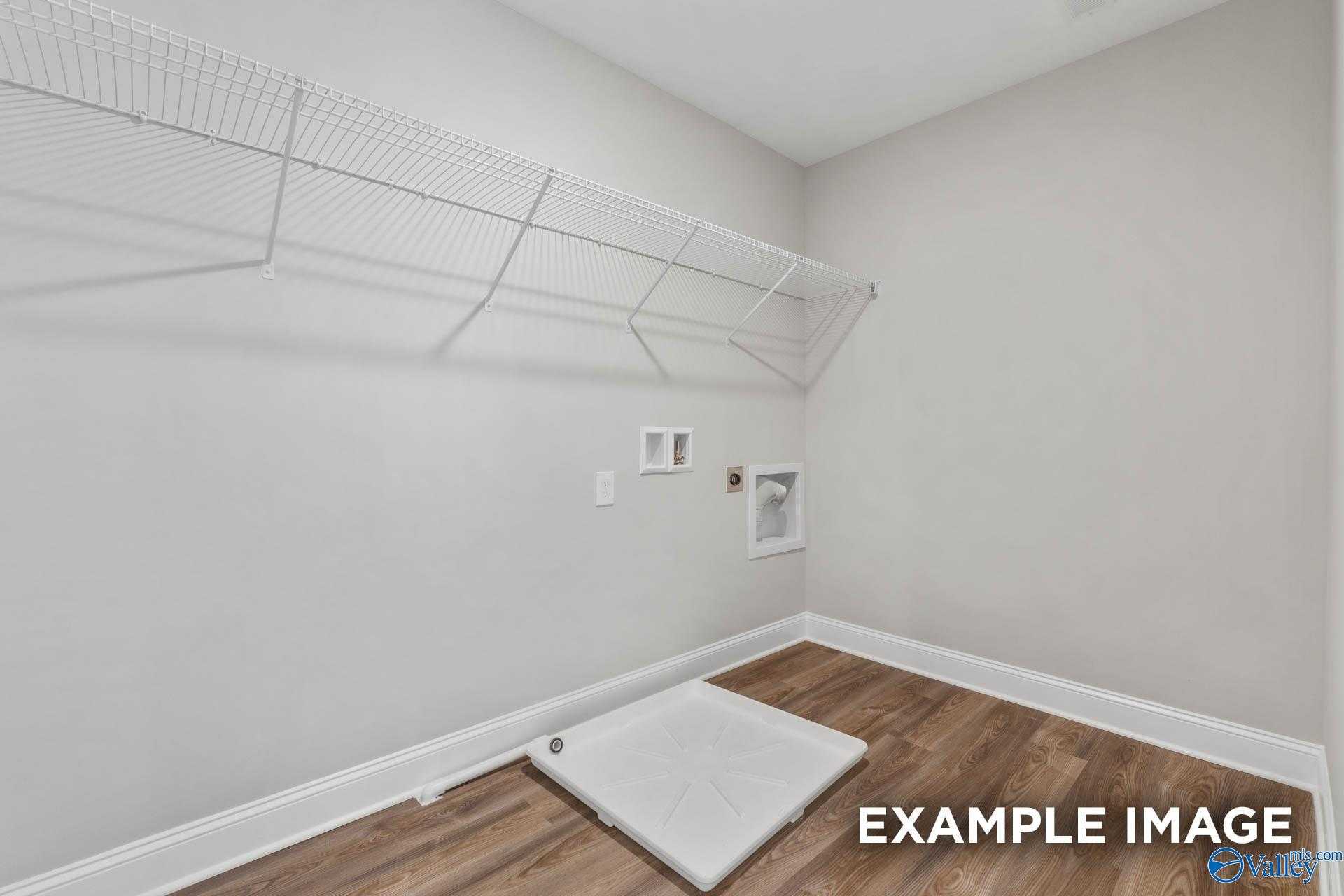 Spacious laundry room with wire shelving, washer dryer hookups, and hardwood floors in Davidson Homes The Shelby B, Athens, Alabama