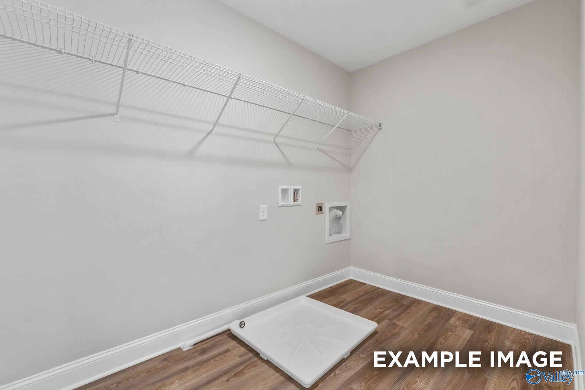 Bright laundry room with wire shelving, washer-dryer hookups, hardwood floors in Davidson Homes Shelby B, New Market, Alabama