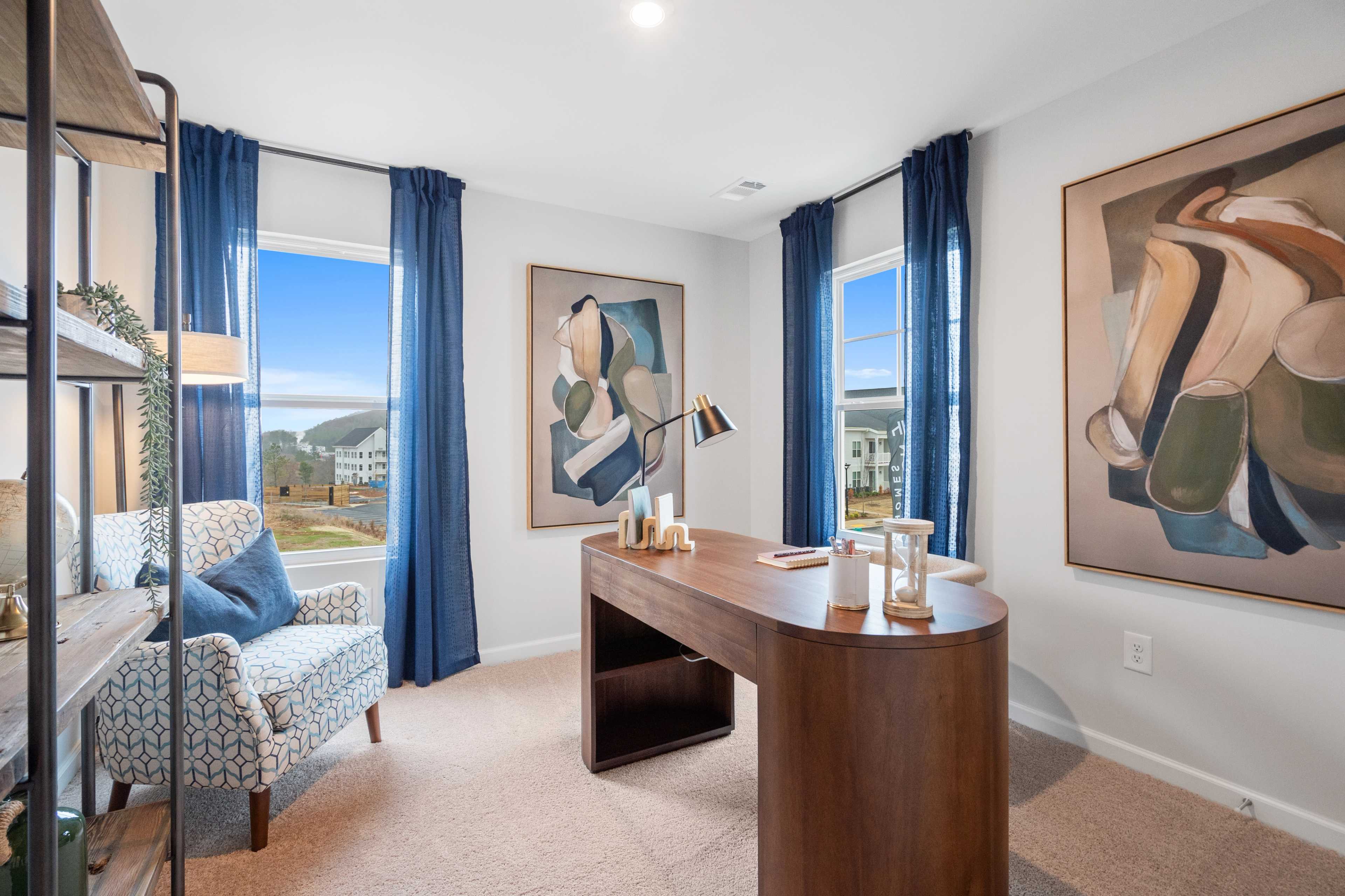 Cozy home office at Stegall Village in Emerson Georgia by Davidson Homes with wooden desk blue curtains and abstract wall art