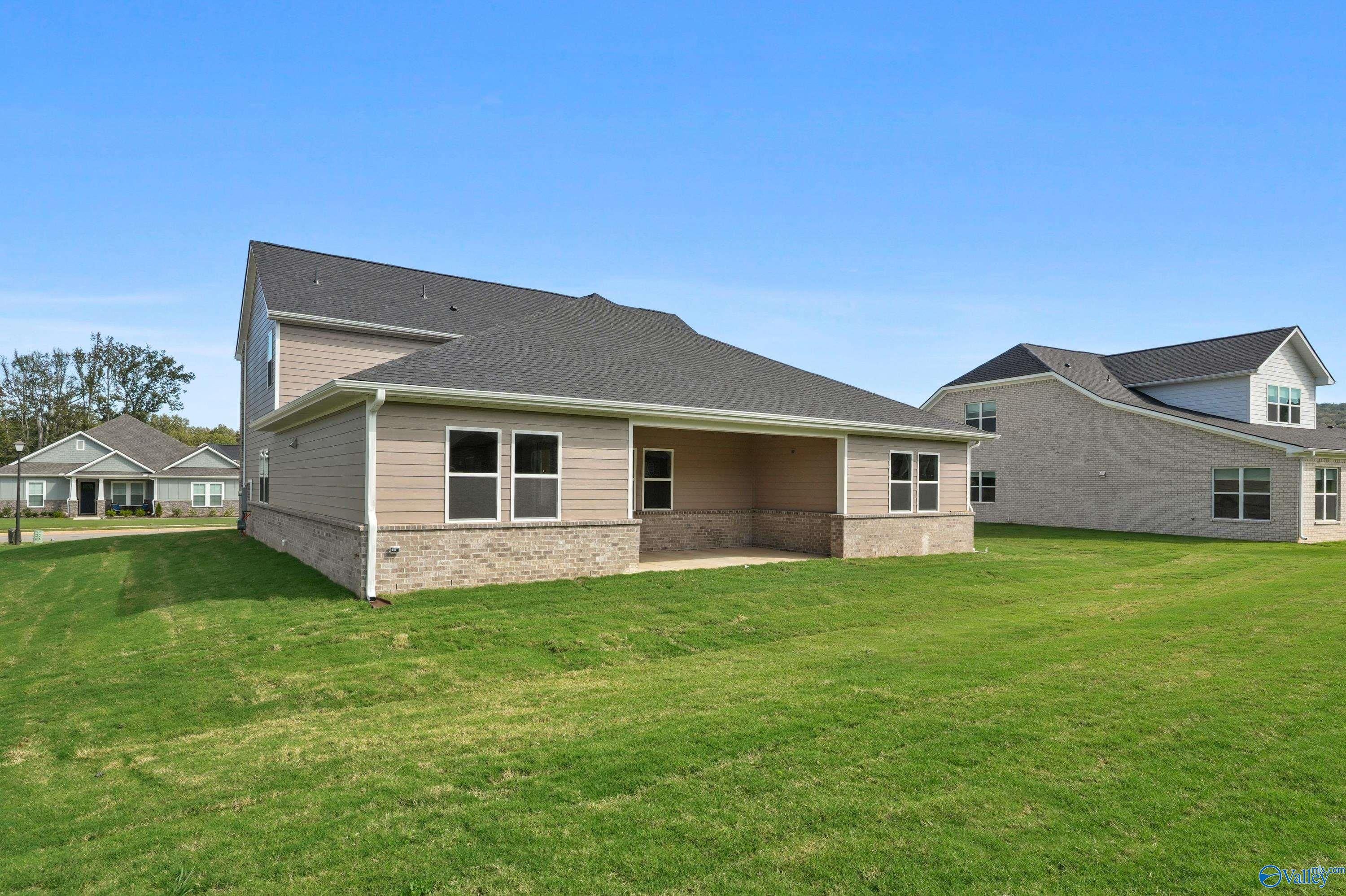 Two-story rear view of Evermore Homes The Haven: 5-bedroom house with covered patio, brick siding, and lush green lawn in Owens Cross Roads, Alabama