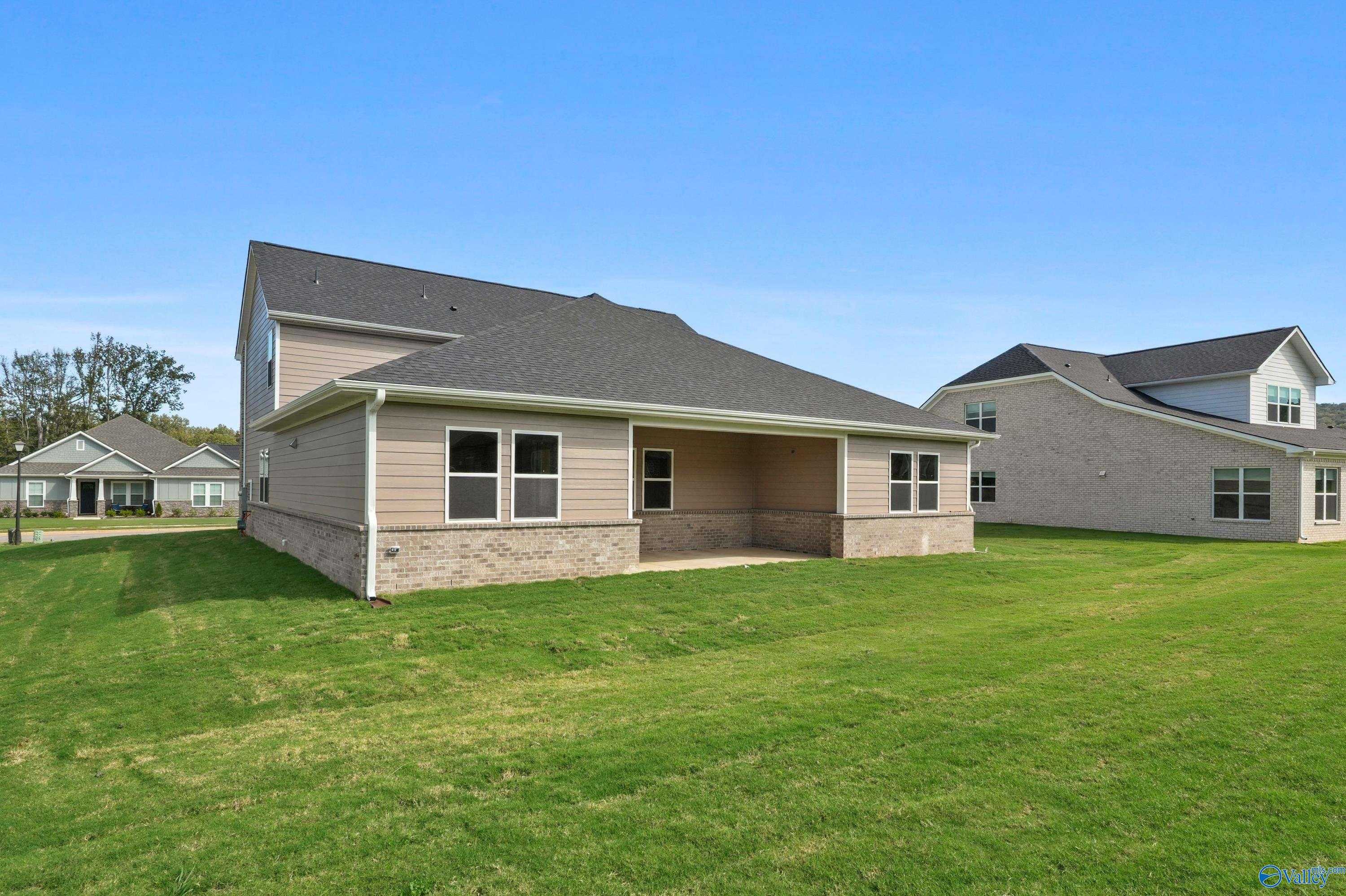 Two-story rear view of Evermore Homes The Haven: 5-bedroom house with covered patio, brick siding, and lush green lawn in Owens Cross Roads, Alabama