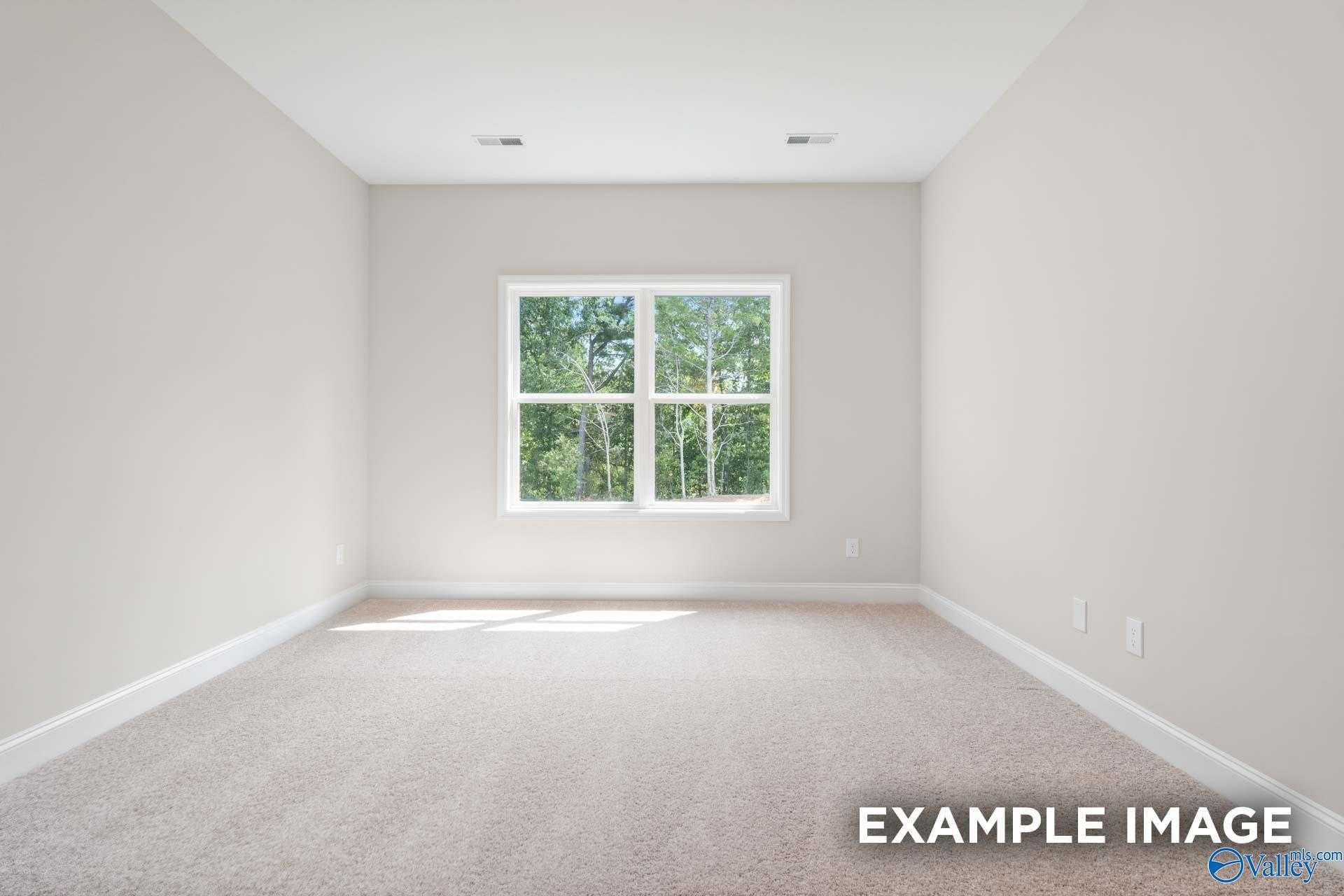 Bright empty bedroom with large window view of trees, neutral walls and carpet in The Franklin 3-bedroom home, Meridianville, Alabama