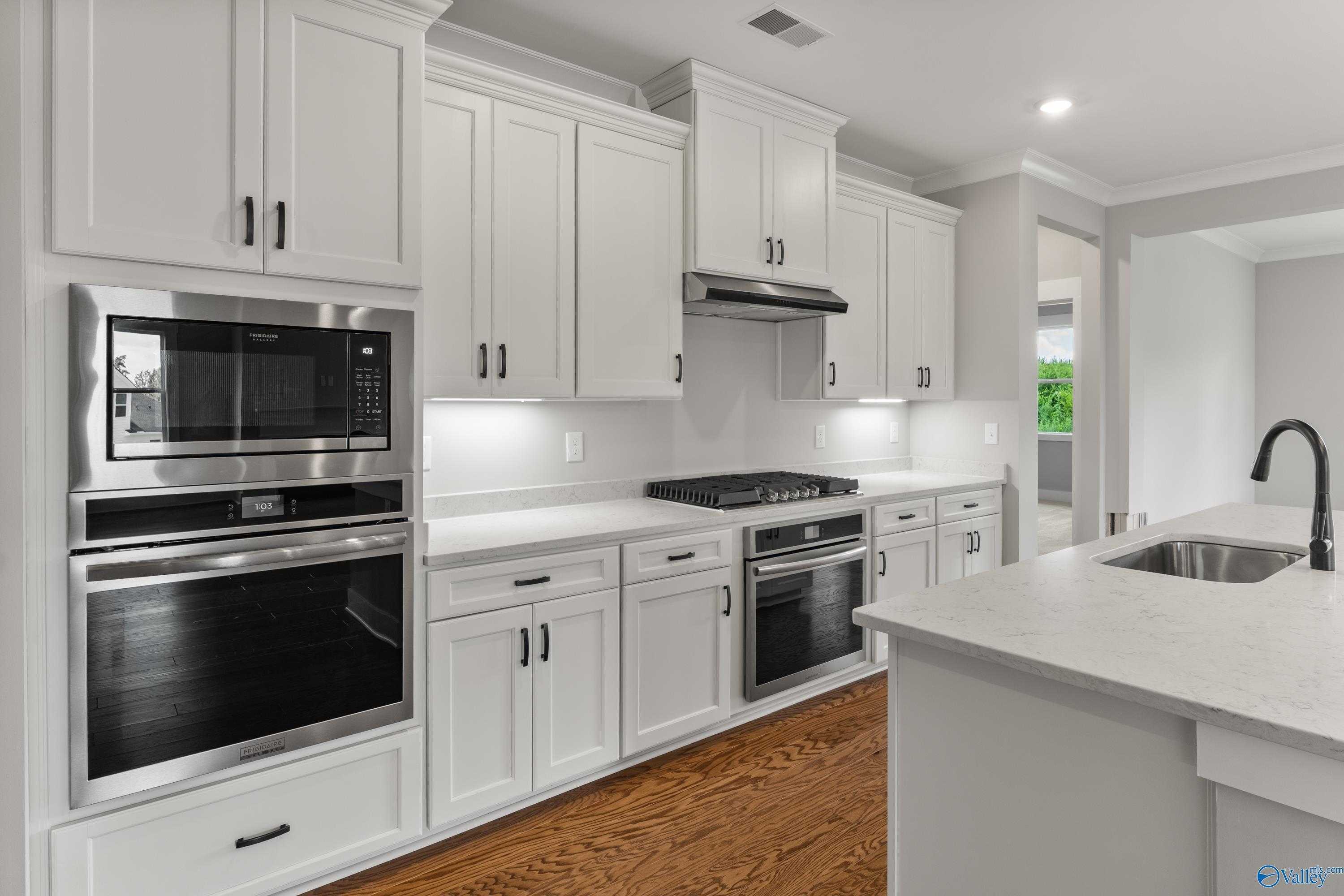 Modern white kitchen with shaker cabinets, stainless double ovens, quartz island in Davidson Homes The Arcadia, Huntsville, Alabama