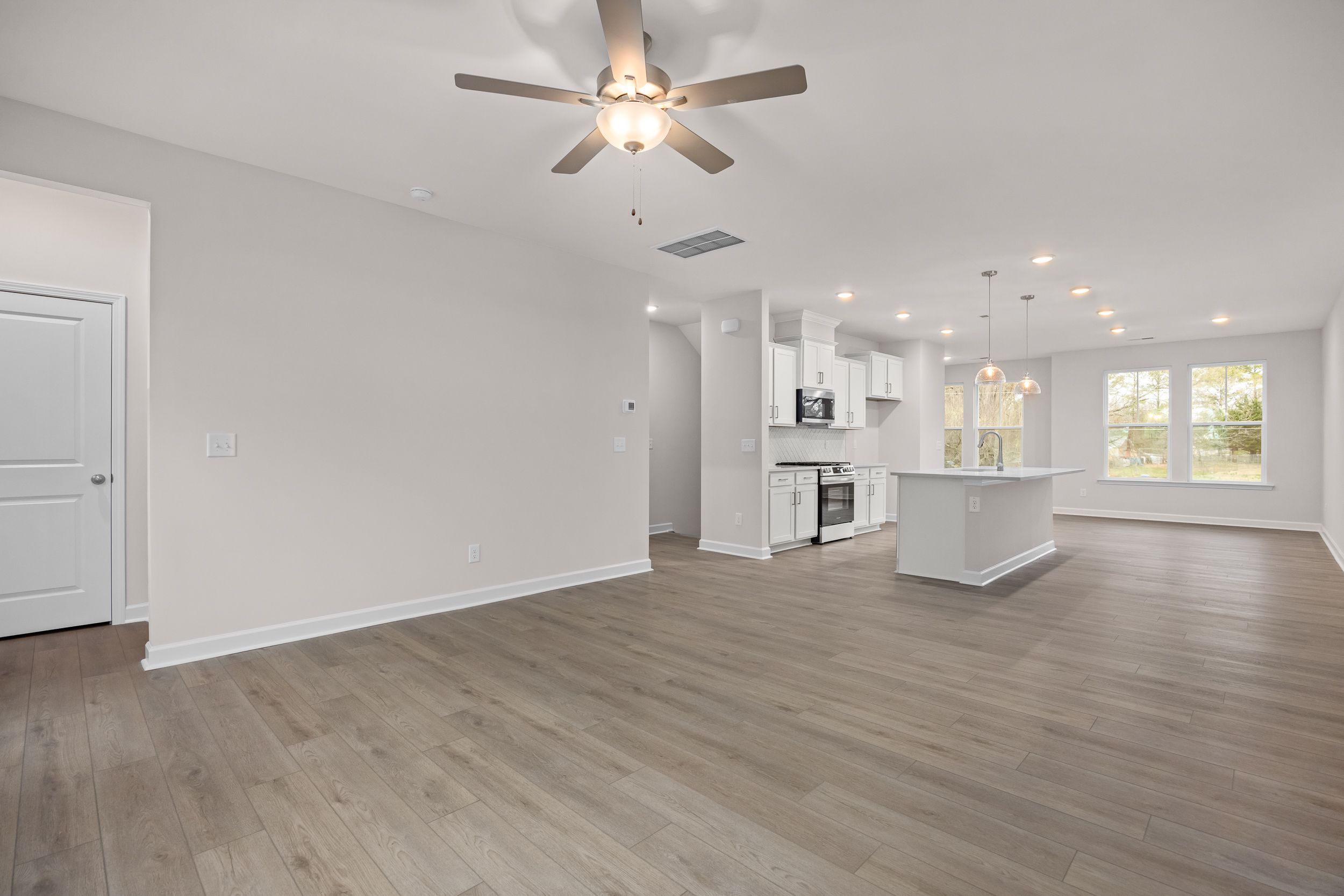 Open-concept kitchen and living area at Forestville Yard Townhomes in Knightdale NC with hardwood floors, white cabinets and large windows