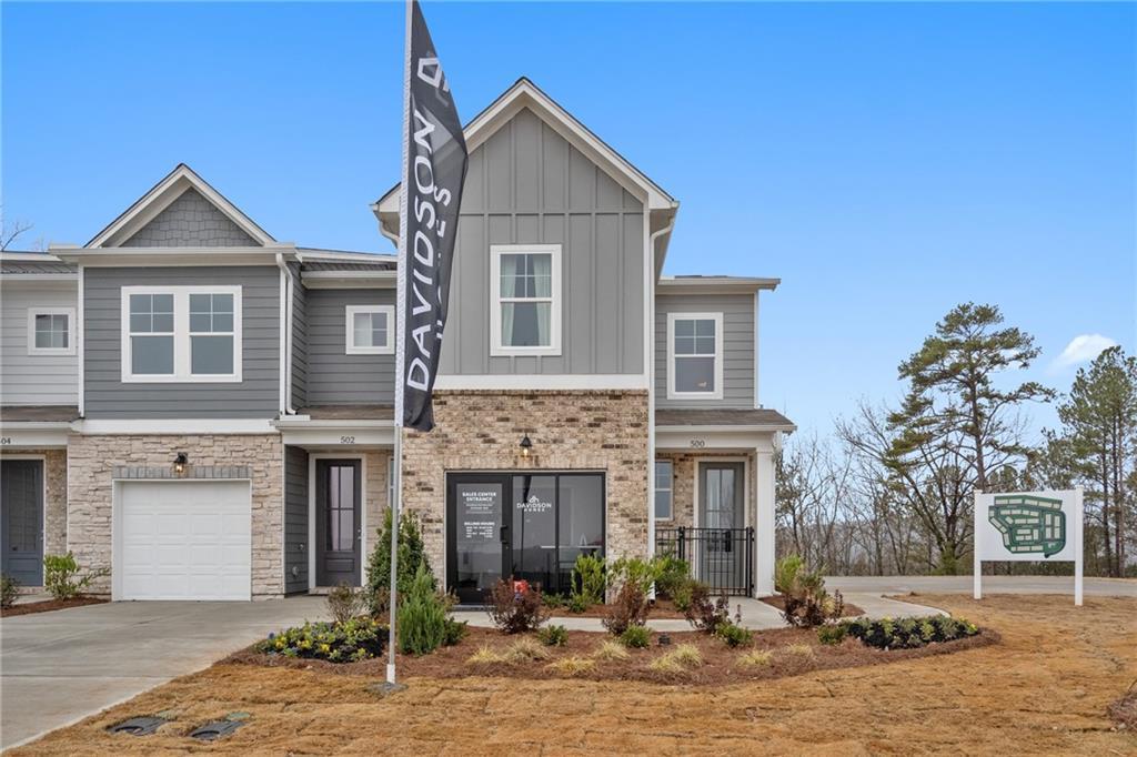 Modern 2-story gray Wilmington B home with brick accents, 1-car garage, and Davidson Homes flag in Stegall Village, Emerson, GA