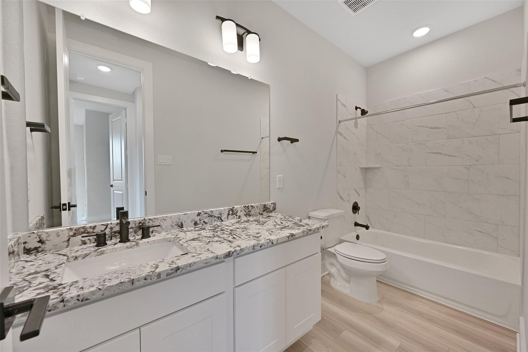 Modern master bathroom with double vanity, swirled quartz countertop, subway tile shower, tub in Davidson Homes The Edward C, Lago Mar, Texas City
