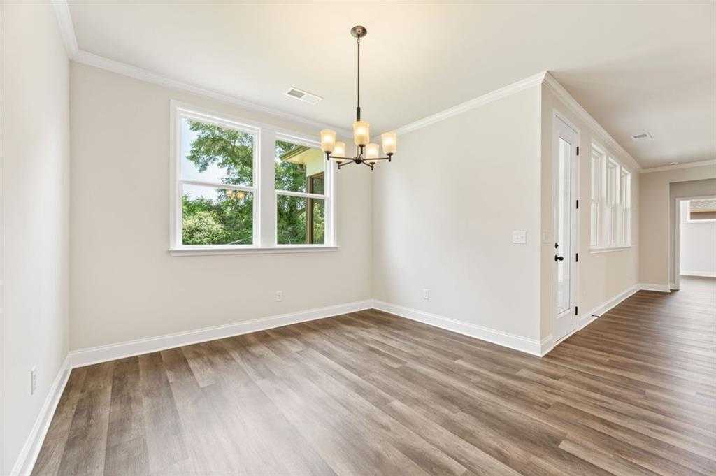 Bright dining room with chandelier, hardwood floors, and large windows in Davidson Homes The Harrison G, Hoschton, GA