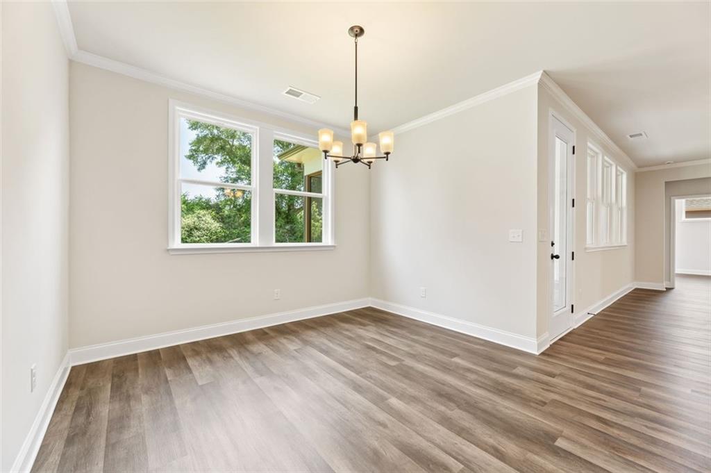 Elegant dining room with hanging chandelier, large windows, and hardwood floors in Davidson Homes The Harrison G, Hoschton, GA
