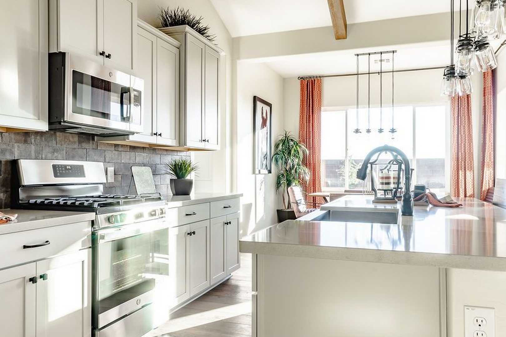 Spacious gourmet kitchen in The Monarch A featuring white shaker cabinets, stainless appliances, large island, and open dining nook
