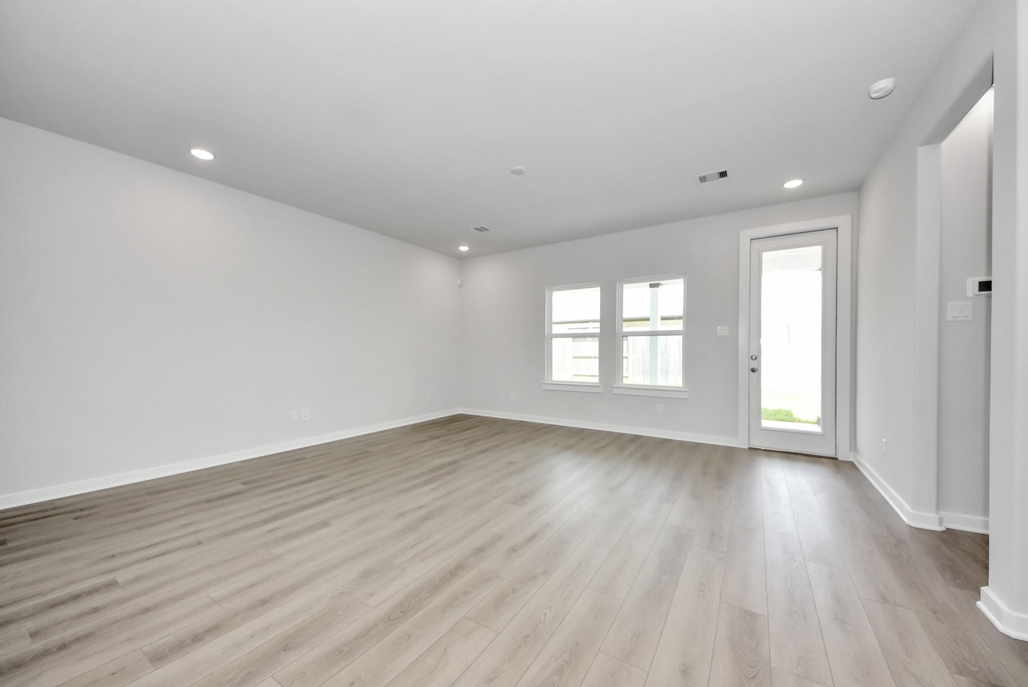 Spacious, light-filled living area with wood-look flooring in The Verano B home by Davidson Homes in Sunterra, Katy, Texas.