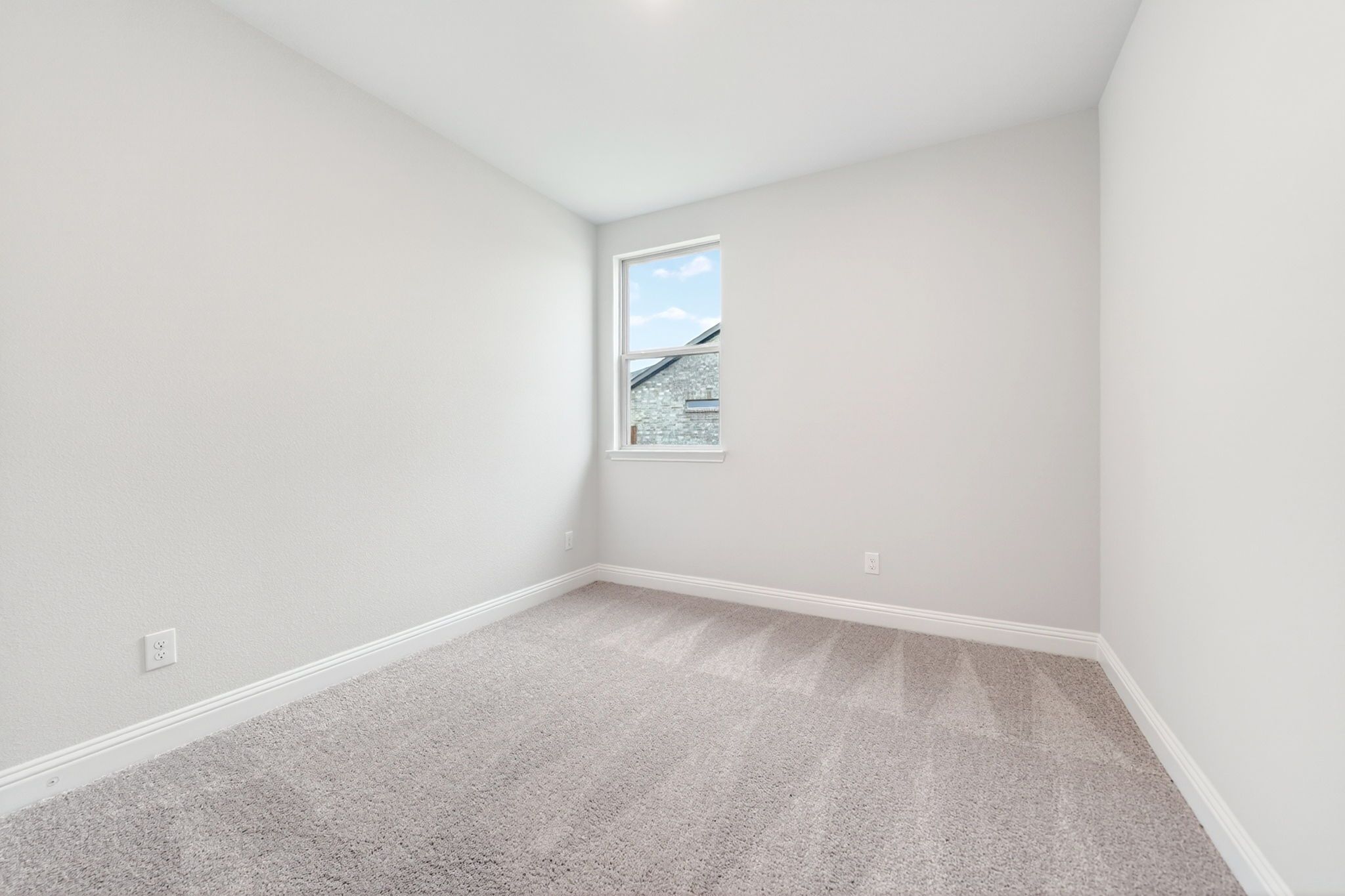 Bright, carpeted bedroom in The Redbud home design by Davidson Homes featuring neutral walls and natural lighting.