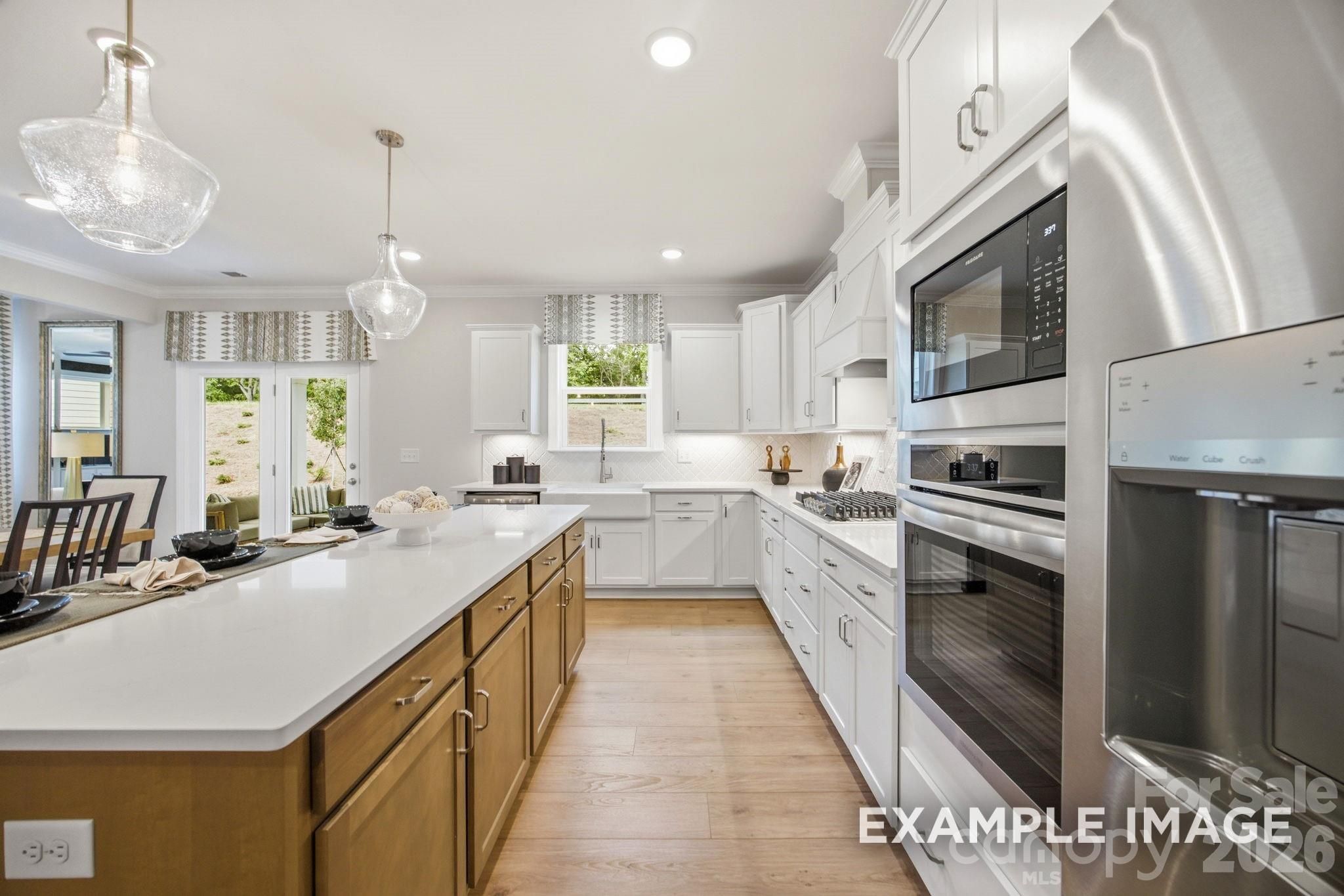 Modern kitchen with white cabinets, wood island, and stainless appliances in The Hickory B II floor plan at Windgate.