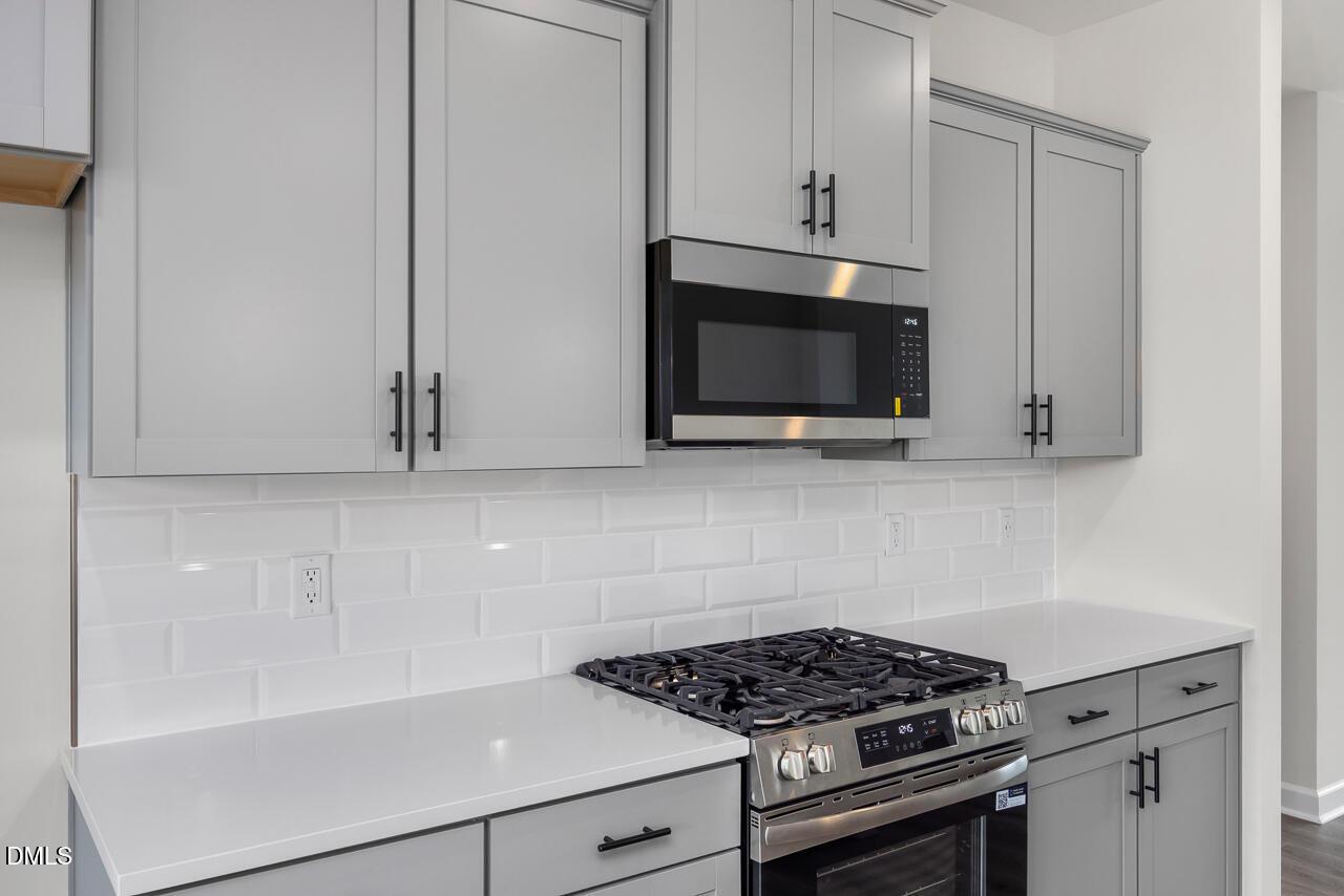 Modern kitchen with grey cabinets, white countertops, and subway tile backsplash in The Mitchell floor plan, Knightdale, NC.