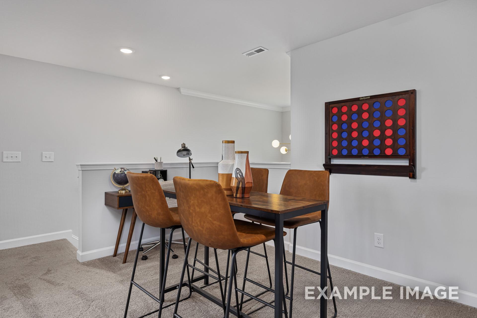 Upper floor loft in The Adalynn A featuring wooden desk, leather chairs, and red-blue Connect Four game wall