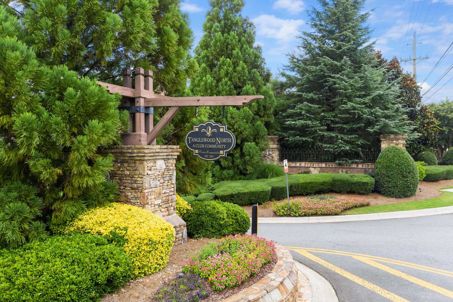 Tanglewood neighborhood entrance in East Cobb Georgia with stone pillars wooden archway lush shrubs and evergreens