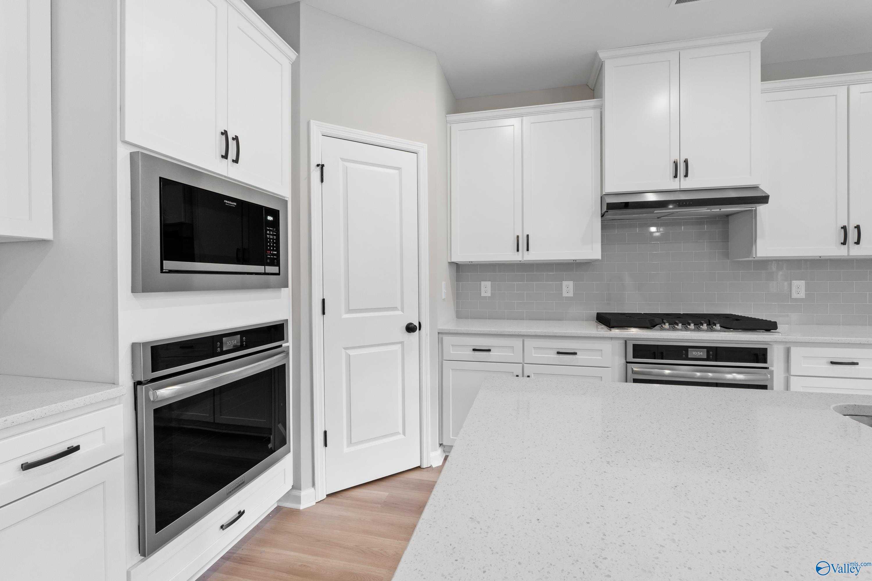 Modern white kitchen featuring double oven, quartz counters, subway tile backsplash in Davidson Homes The Dorado, Huntsville AL