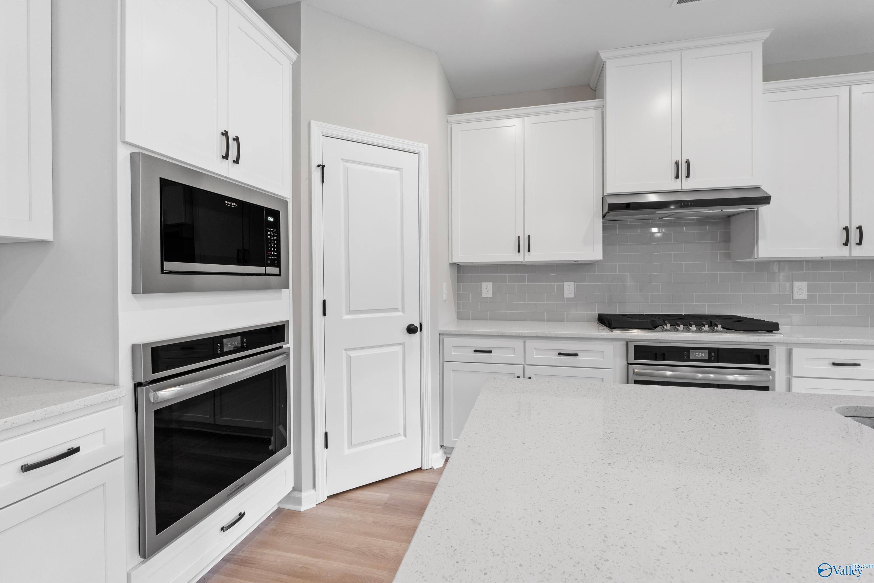 Modern white kitchen featuring double oven, quartz counters, subway tile backsplash in Davidson Homes The Dorado, Huntsville AL