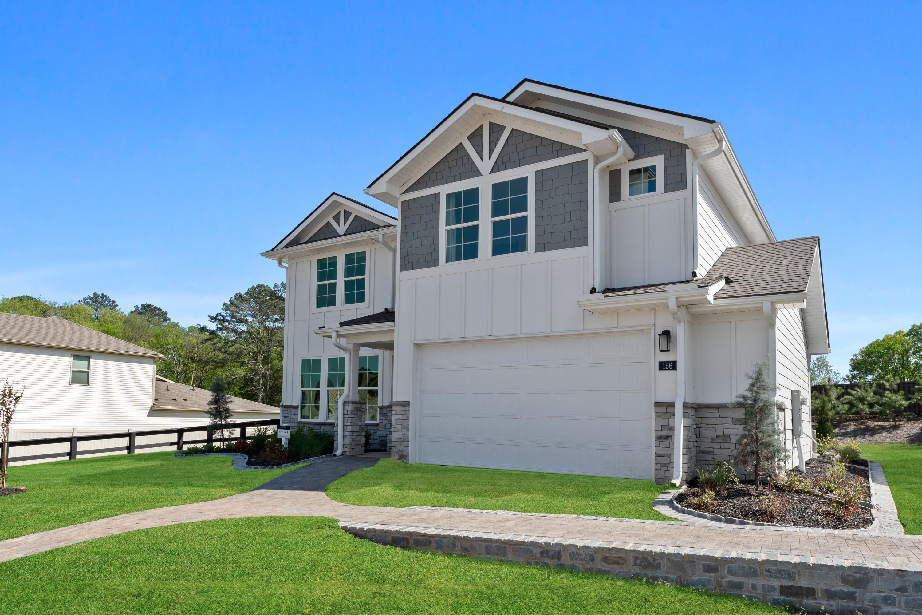 Two-story modern home exterior at Evergreen Mill in Madison, Alabama with white siding, gray accents, garage, and landscaped yard
