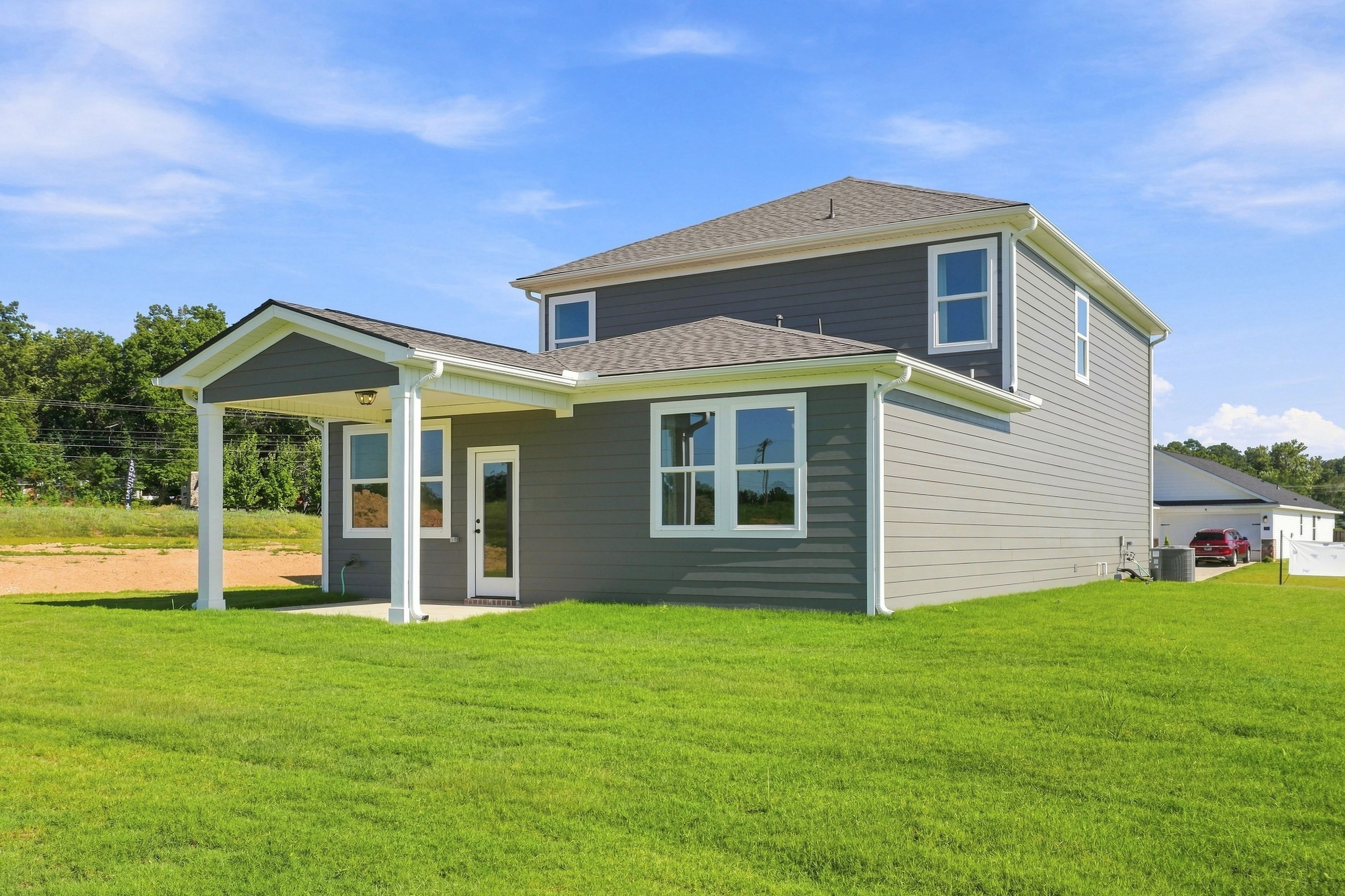 Two-story gray home with covered porch and green lawn at Bailey Park by Davidson Homes in Fayetteville, Tennessee