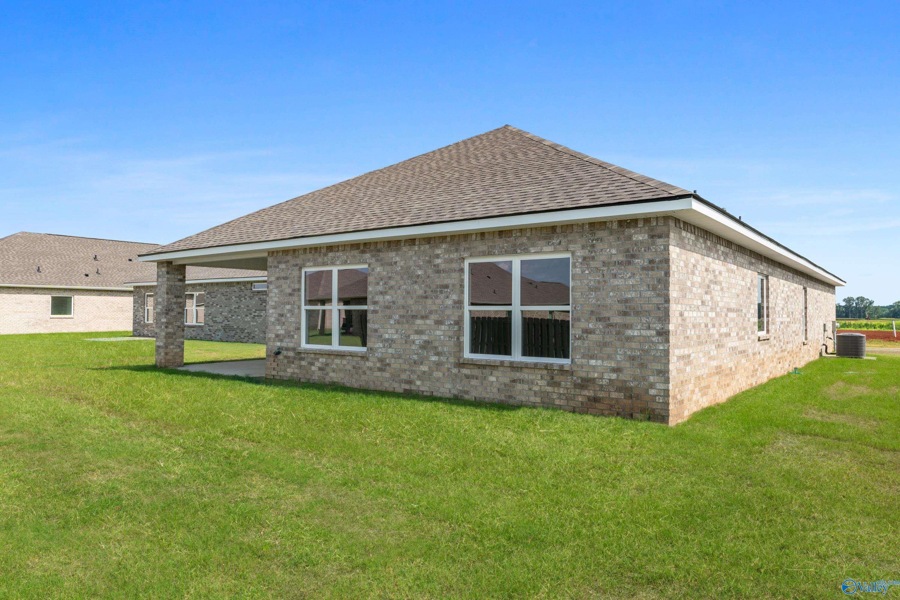 Brick single-story home side view with gabled roof, large windows, covered carport on green lawn in Ivy Hills, Toney, Alabama