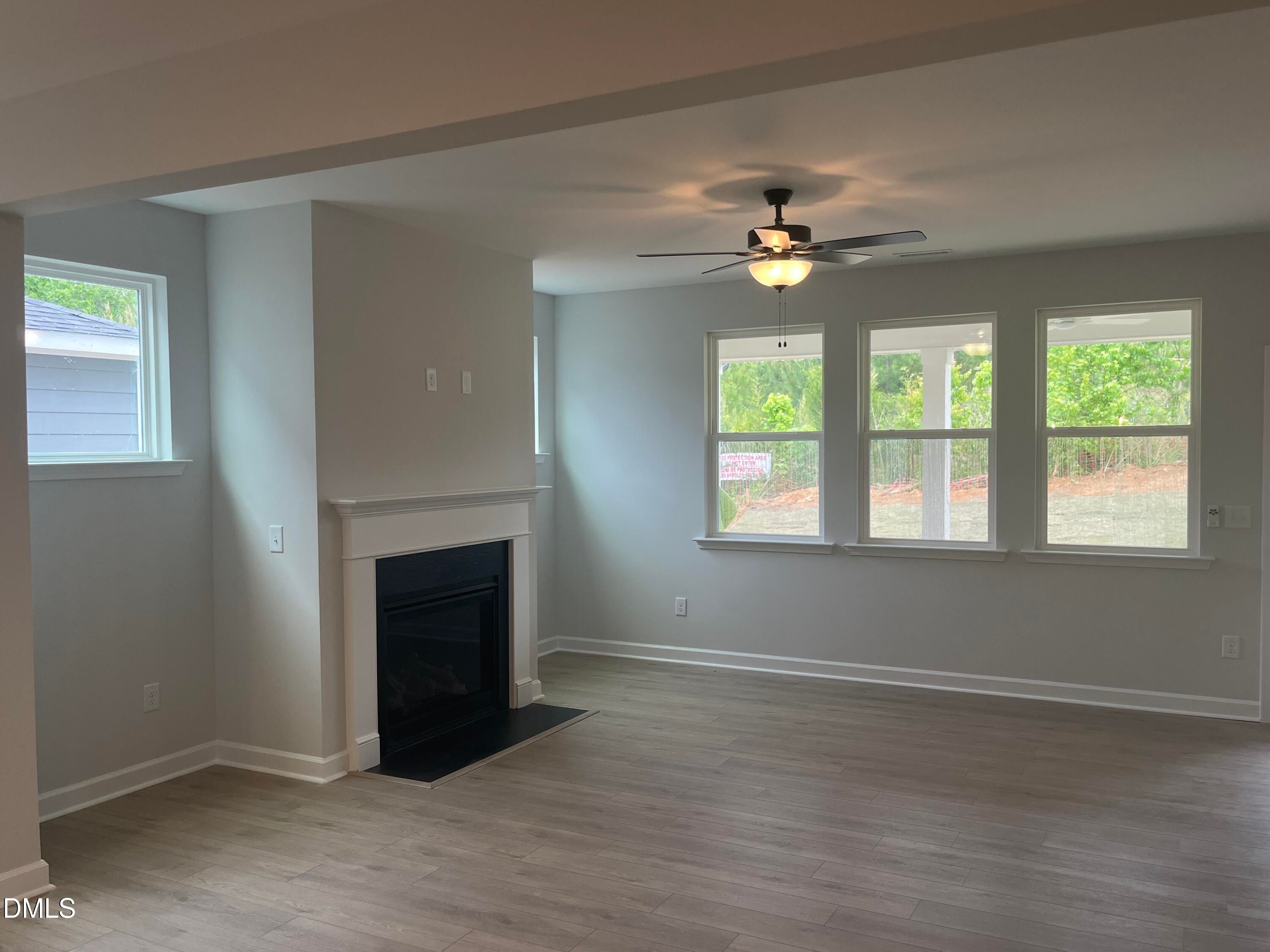 Cozy family room featuring gas fireplace, large windows with backyard view, hardwood floors in Davidson Homes The Birch II E, Wake Forest