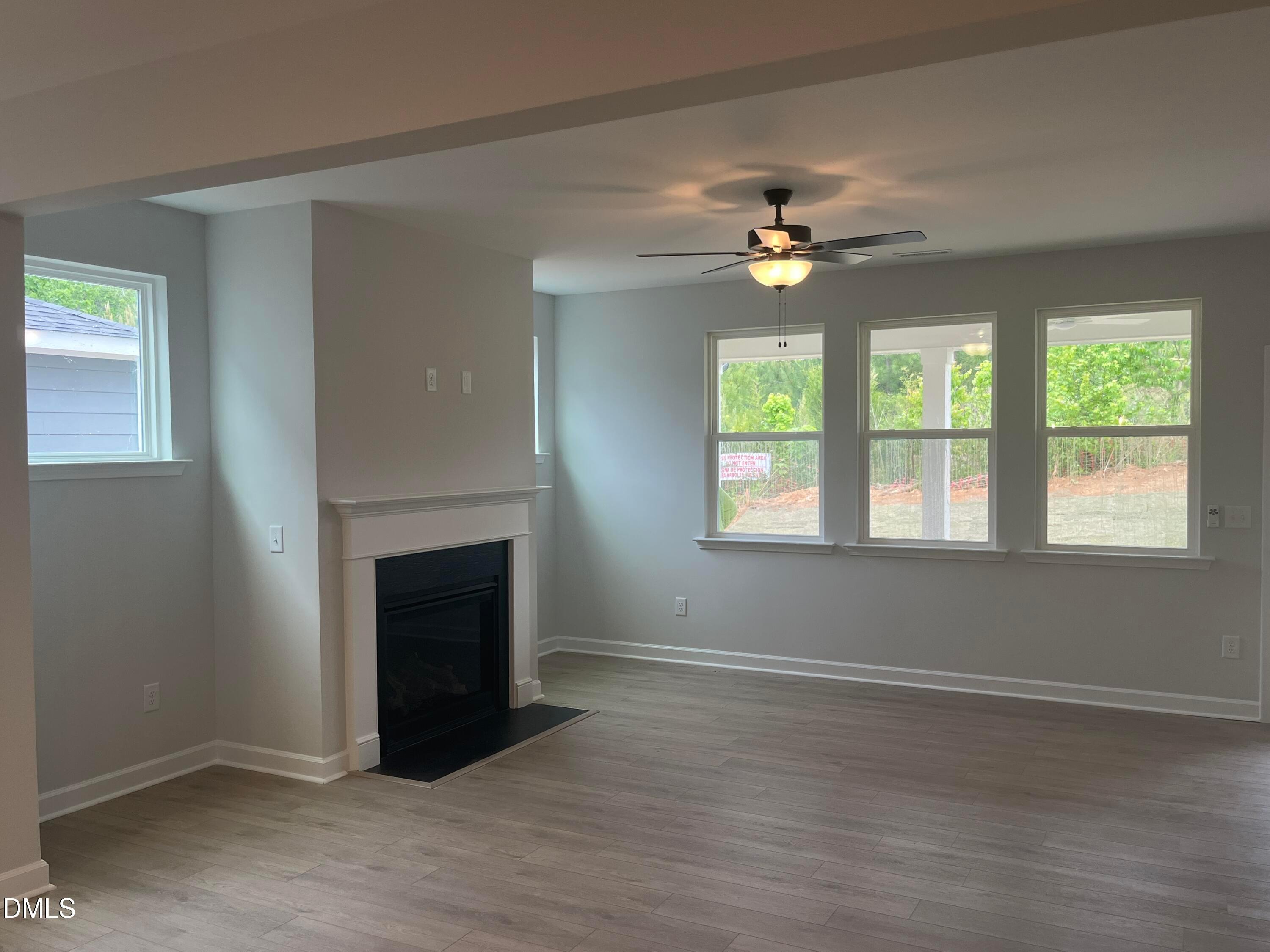 Cozy family room featuring gas fireplace, large windows with backyard view, hardwood floors in Davidson Homes The Birch II E, Wake Forest