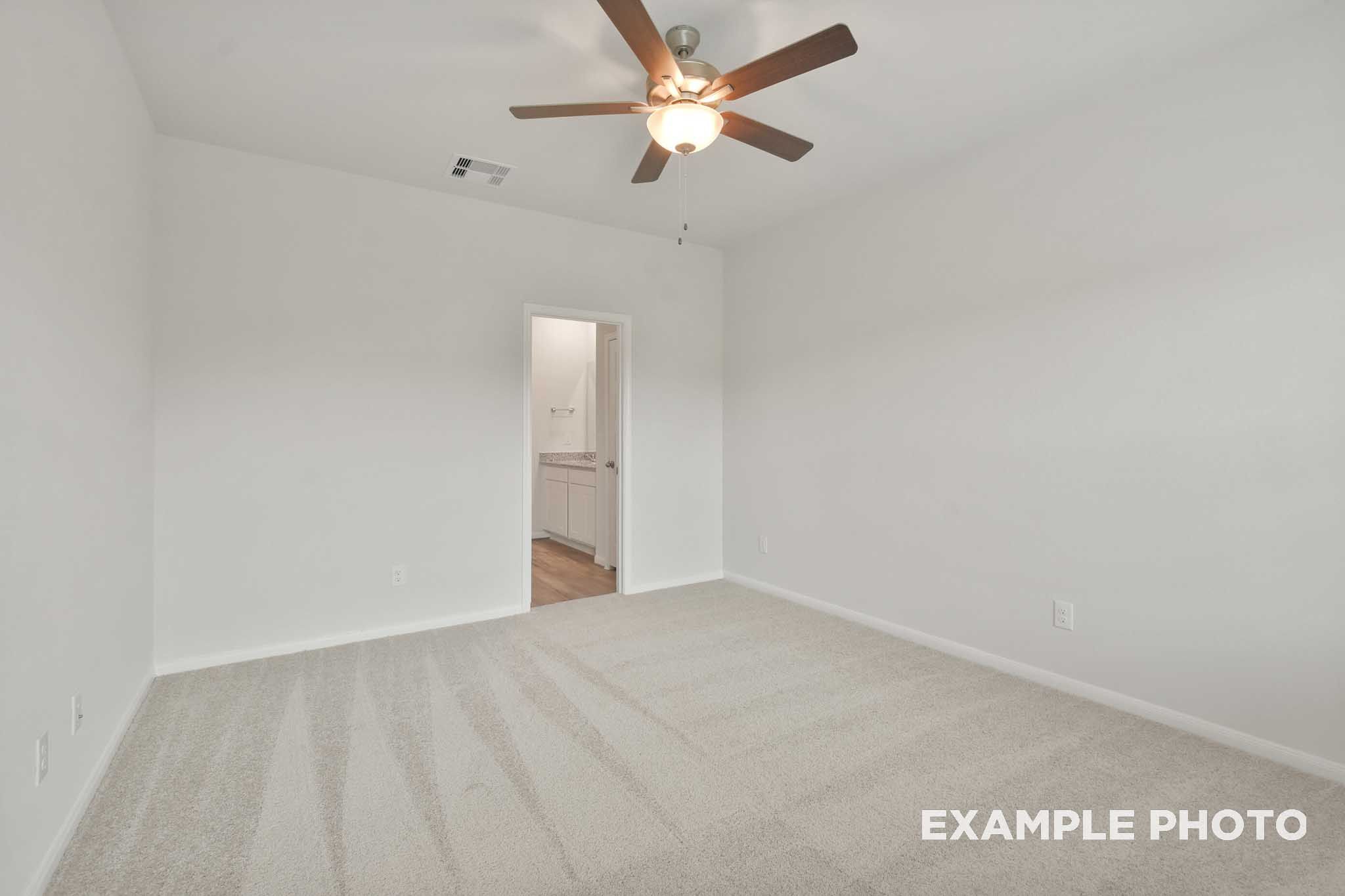 Spacious primary bedroom in The Brazos by Davidson Homes featuring ceiling fan, carpet flooring, and master suite on main floor.