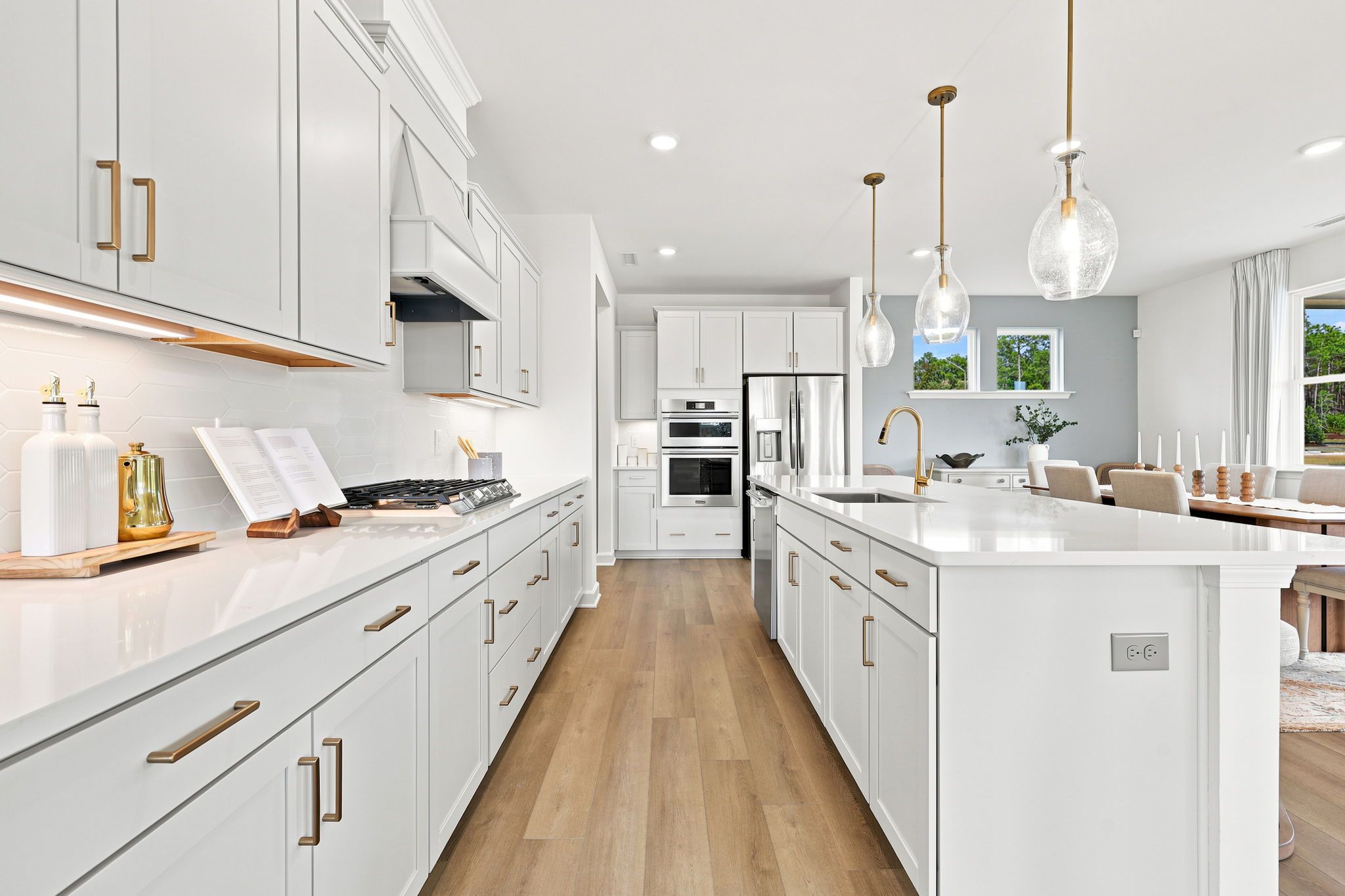 Modern kitchen with white cabinets, quartz countertops, and brass hardware at Montrose in Aberdeen, North Carolina.