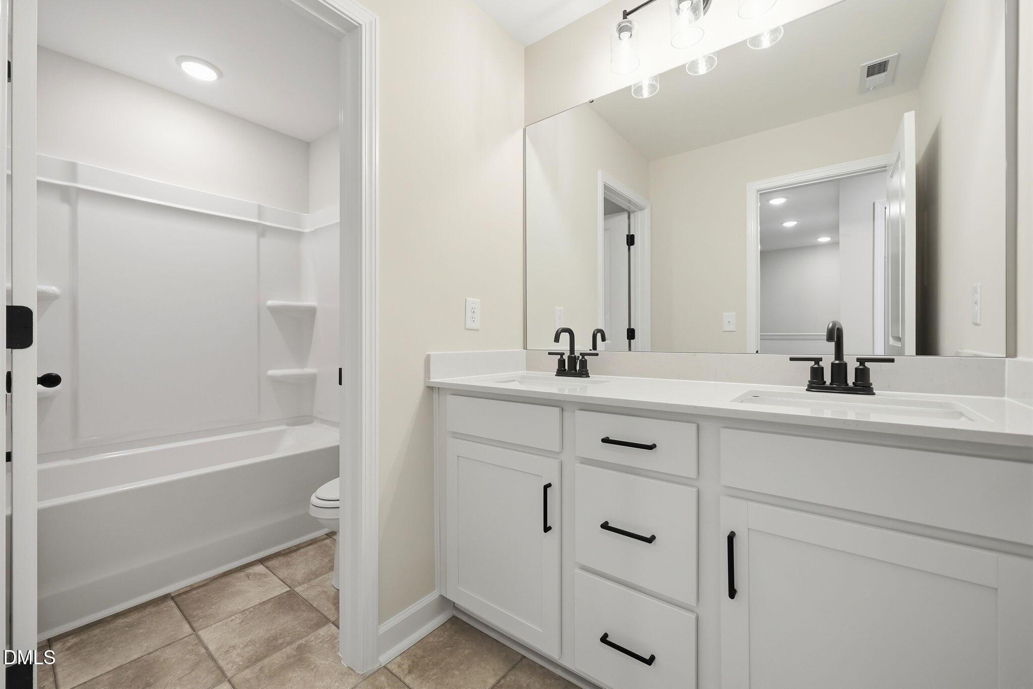 Modern bathroom with dual vanity, white cabinets, and tub-shower combo in The Mitchell Interior plan at Camden Park.