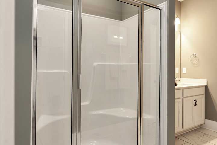 Spacious glass-enclosed walk-in shower in modern bathroom at Williams Pointe, Huntsville AL with white subway tile and vanity