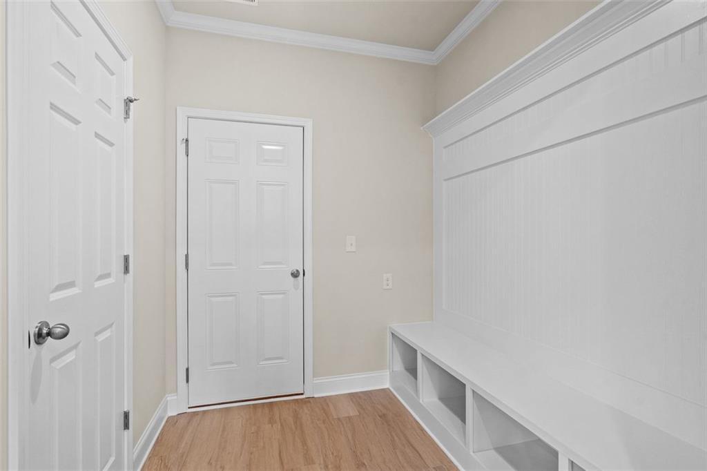 Spacious mudroom with white shiplap cubbies, built-in bench, and double doors in The Hickory B home at Wehunt Meadows, Hoschton