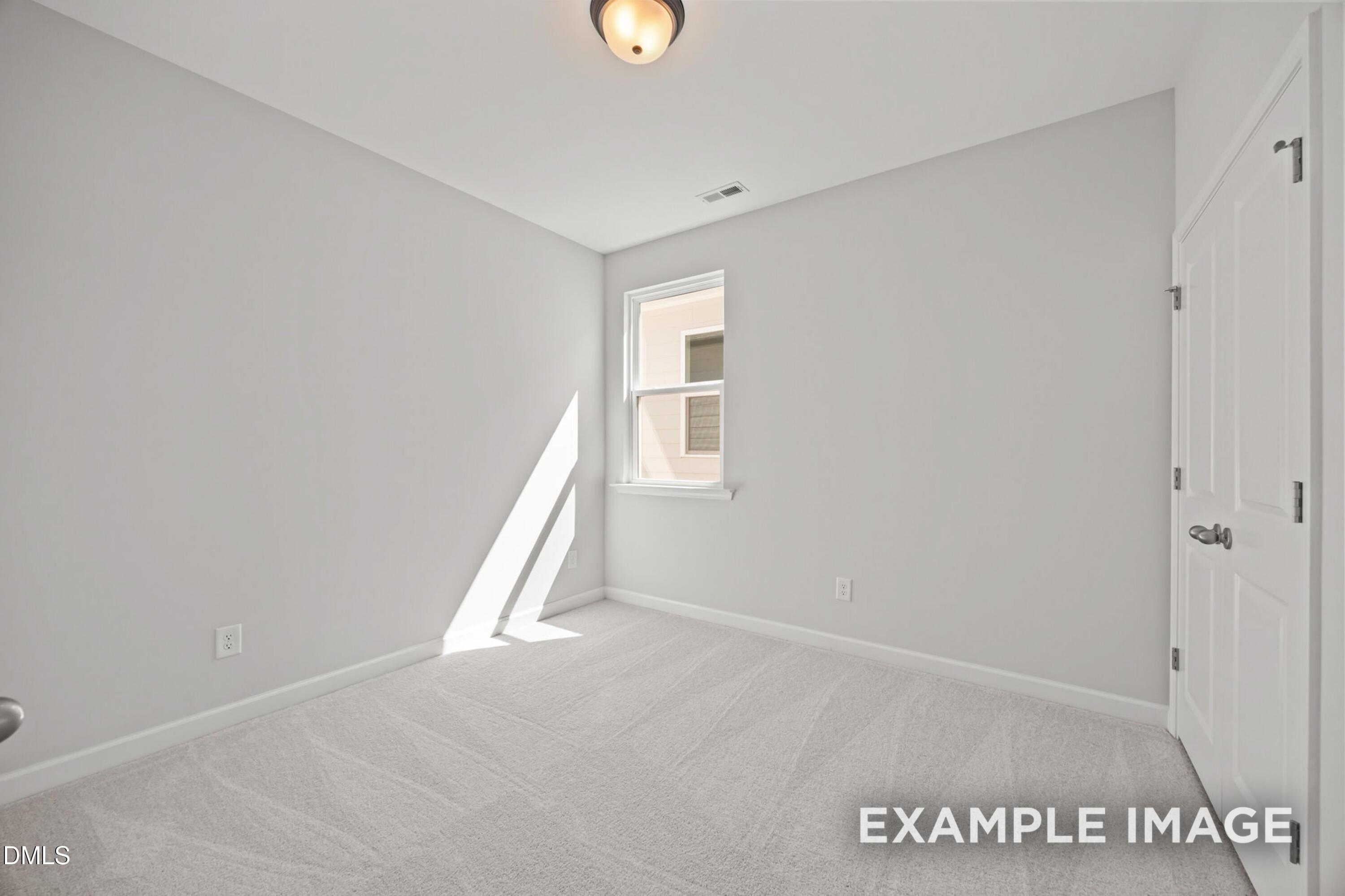 Bright, carpeted bedroom with white walls and natural light in The Alexander B floor plan, Forestville Yard, Knightdale.