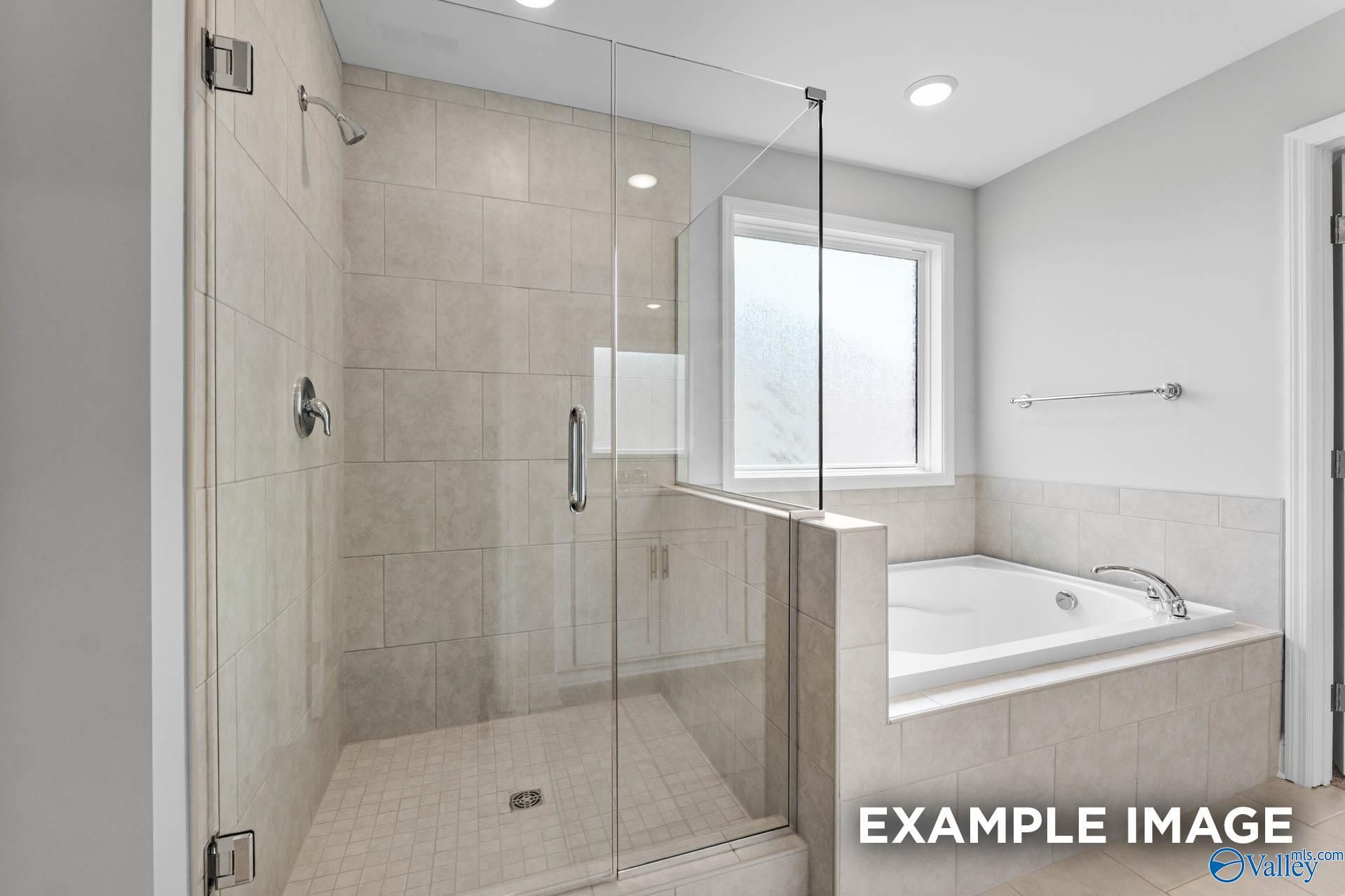 Modern master bathroom featuring frameless glass shower, subway tile, and soaking tub in Davidson Homes The Madison A, Meridianville, AL