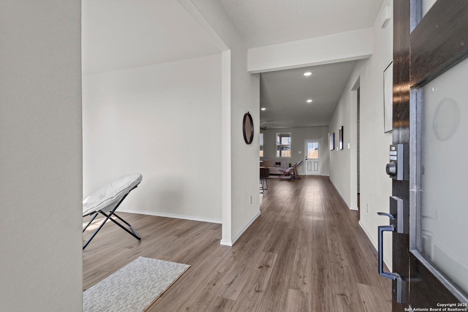 Bright entry hallway with hardwood floors, arched openings, and round mirror in Davidson Homes The Douglas C, Seguin, Texas