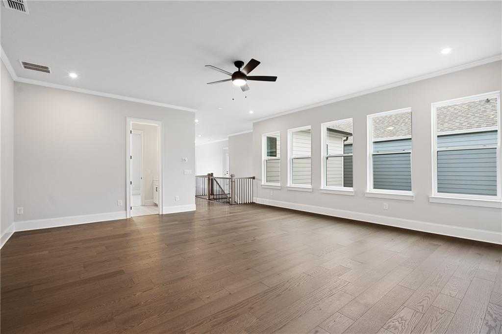 Spacious upstairs loft with hardwood floors, ceiling fan, large windows, and adjacent bath in Davidson Homes The Seaside B, Woodstock, GA