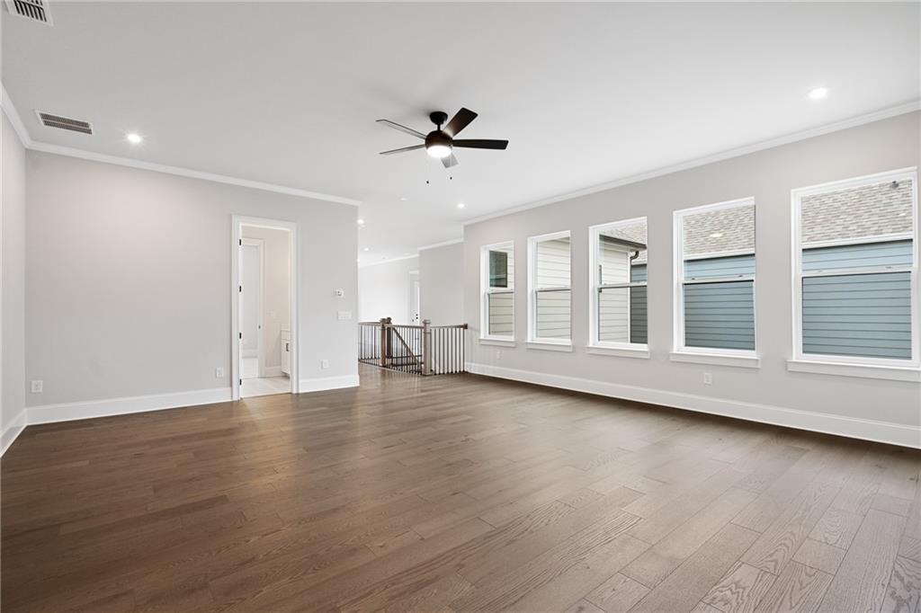 Spacious upstairs loft with hardwood floors, ceiling fan, large windows, and adjacent bath in Davidson Homes The Seaside B, Woodstock, GA