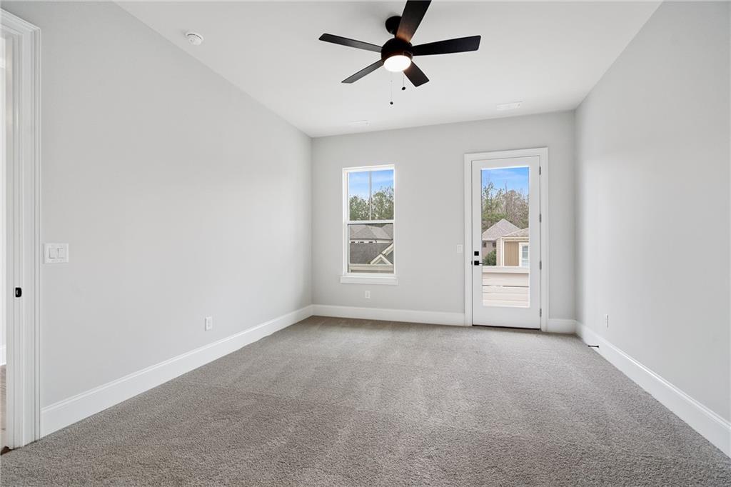 Bright secondary bedroom with ceiling fan, windows, and French door to backyard in Davidson Homes The Seaside B, Woodstock, GA