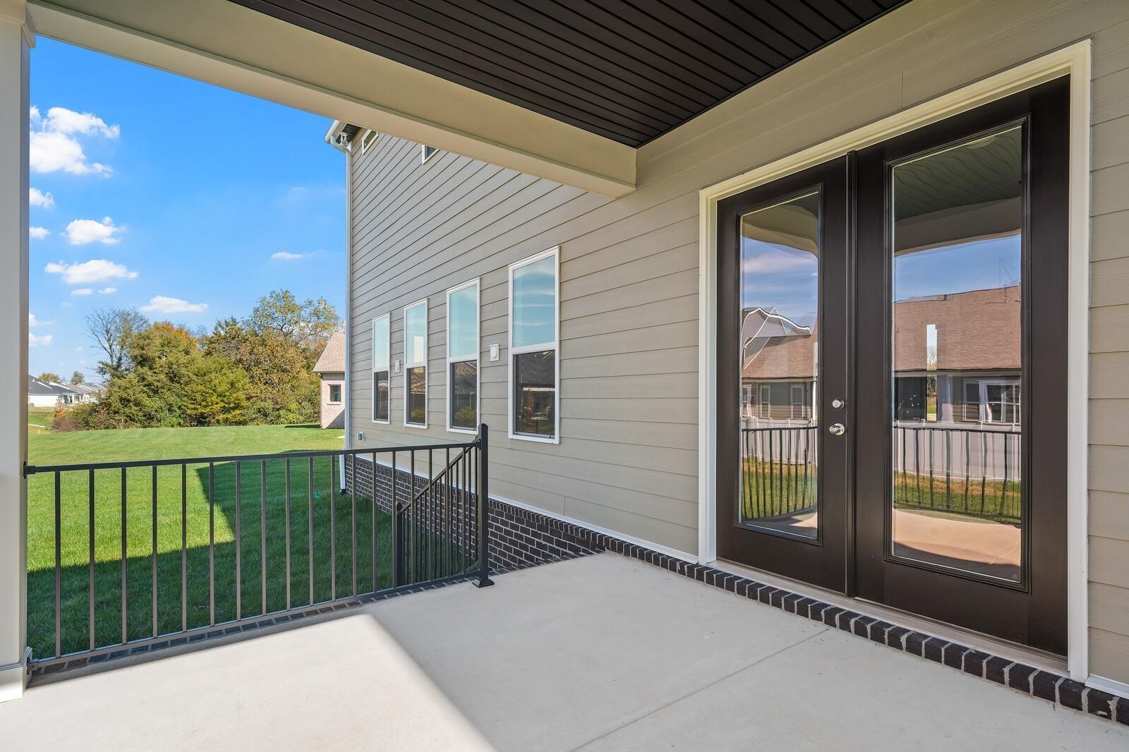 Covered patio with French doors, black railing, and lush green lawn in Davidson Homes The Alston A, Shelton Square, Murfreesboro, Tennessee