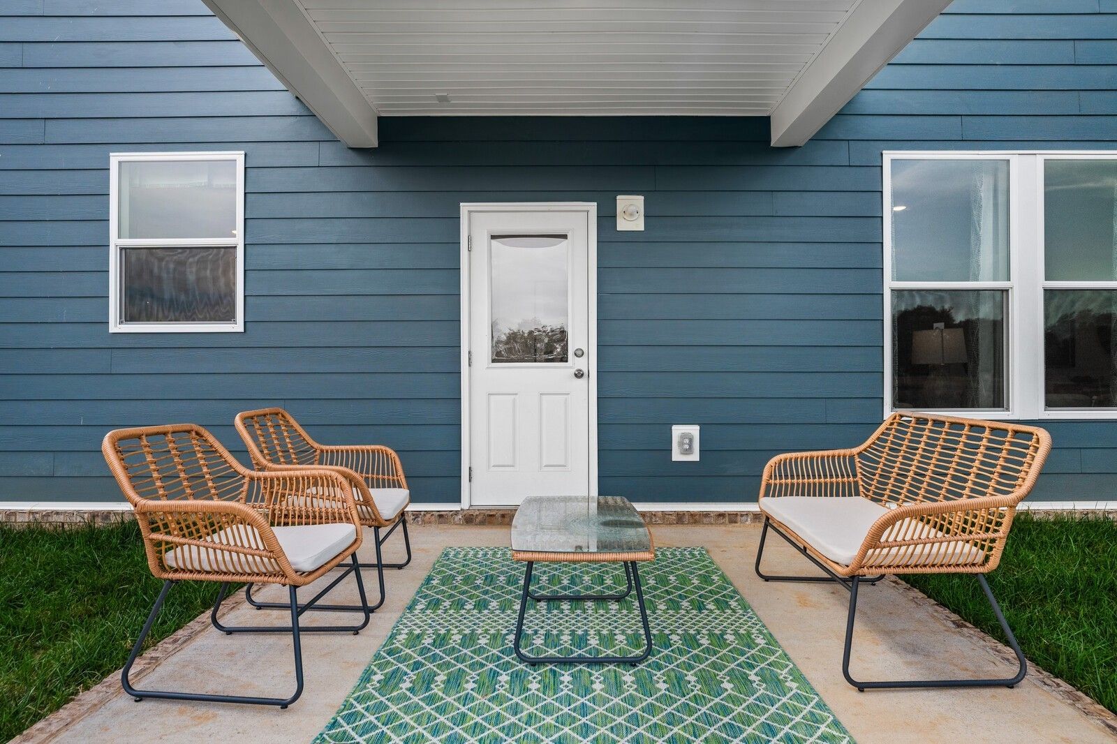 Covered back patio with rattan chairs, loveseat, glass table on green rug in Davidson Homes Gordon C, Sage Farms, White House, TN