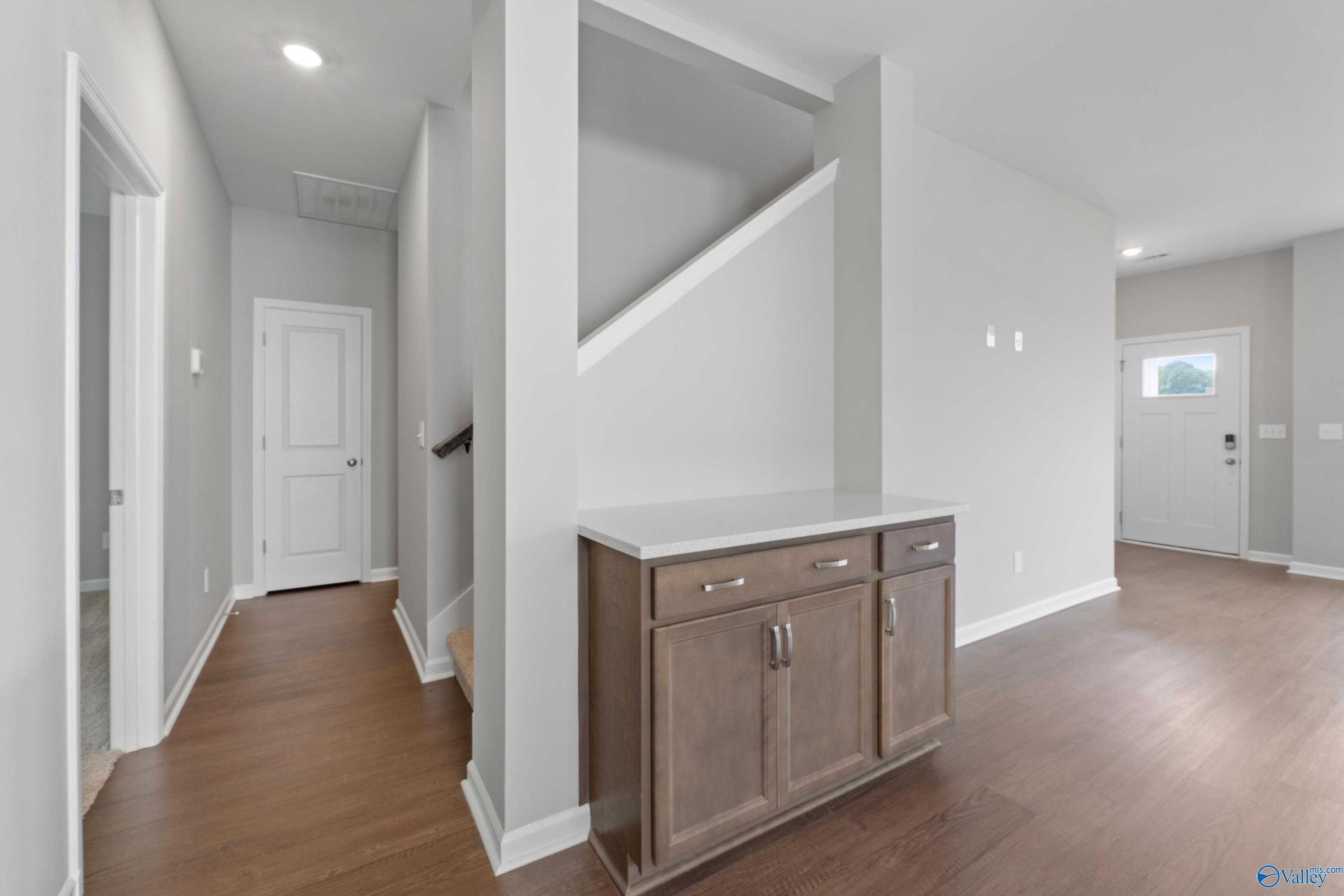 Bright hallway with oak staircase, white doors, and wooden console in The Stella 3-bedroom home, Hazel Green, AL