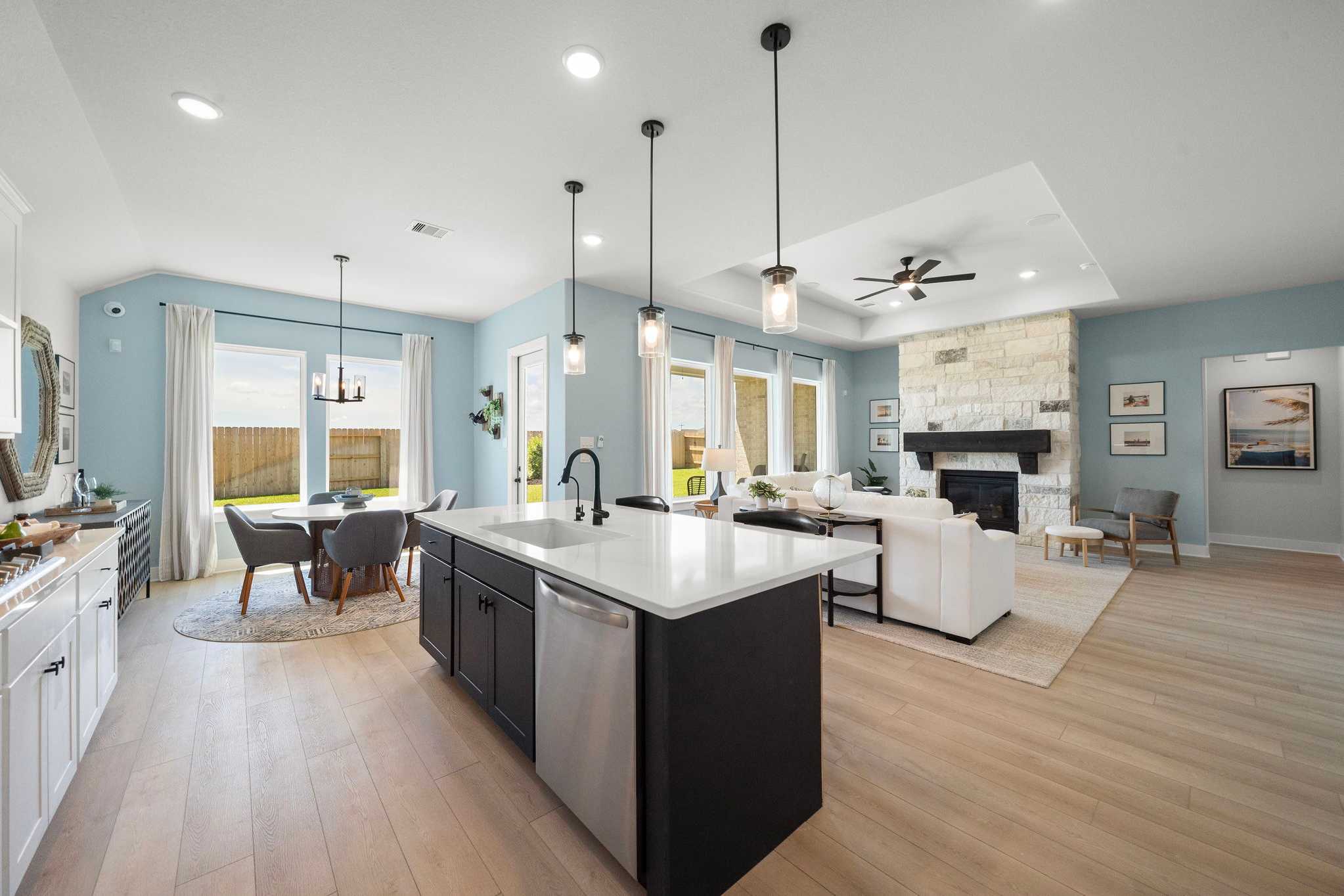 Open-concept kitchen and living room in Lago Mar Texas City TX with quartz island, stone fireplace, hardwood floors by Davidson Homes