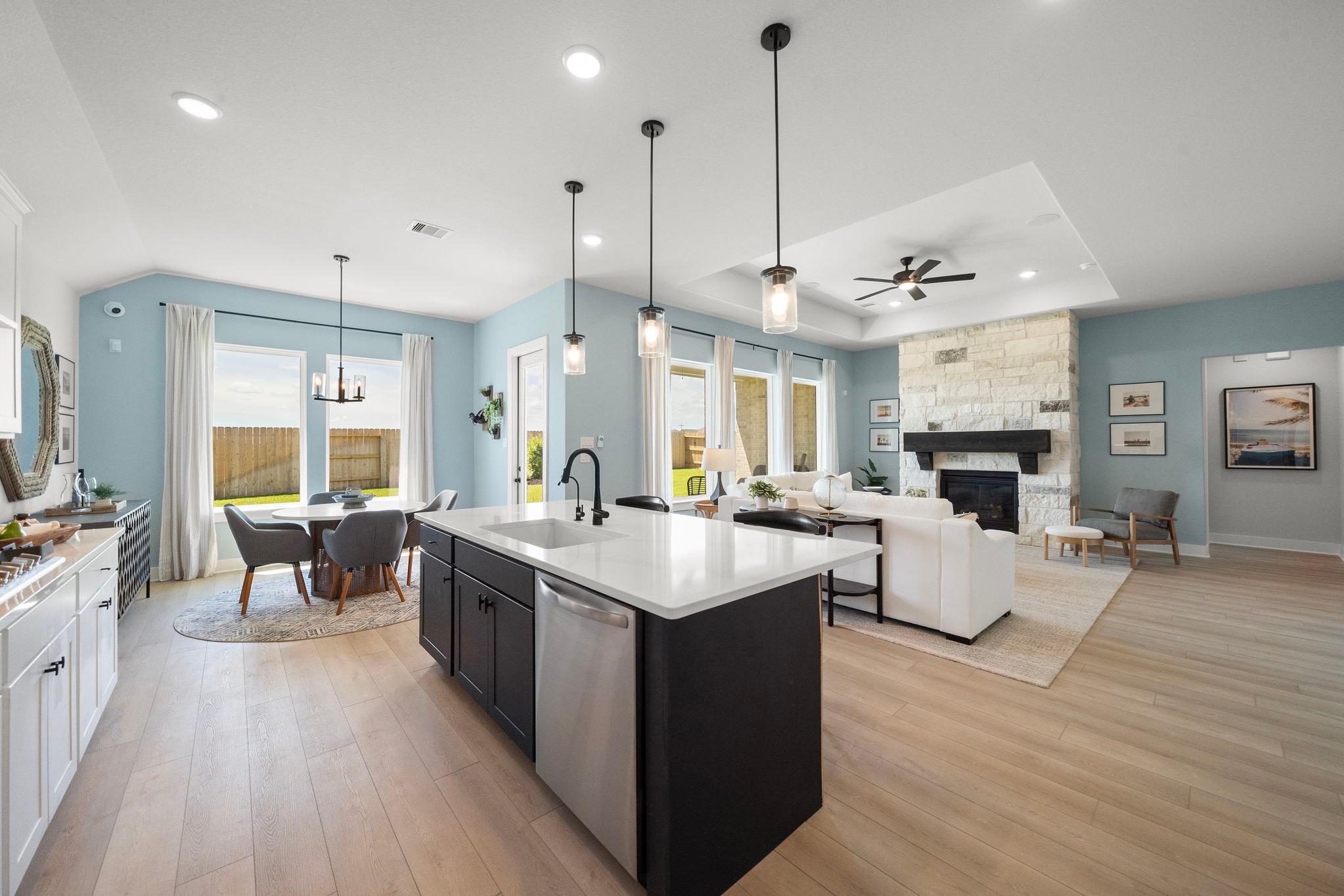 Open-concept kitchen and living room in Lago Mar Texas City TX with quartz island, stone fireplace, hardwood floors by Davidson Homes