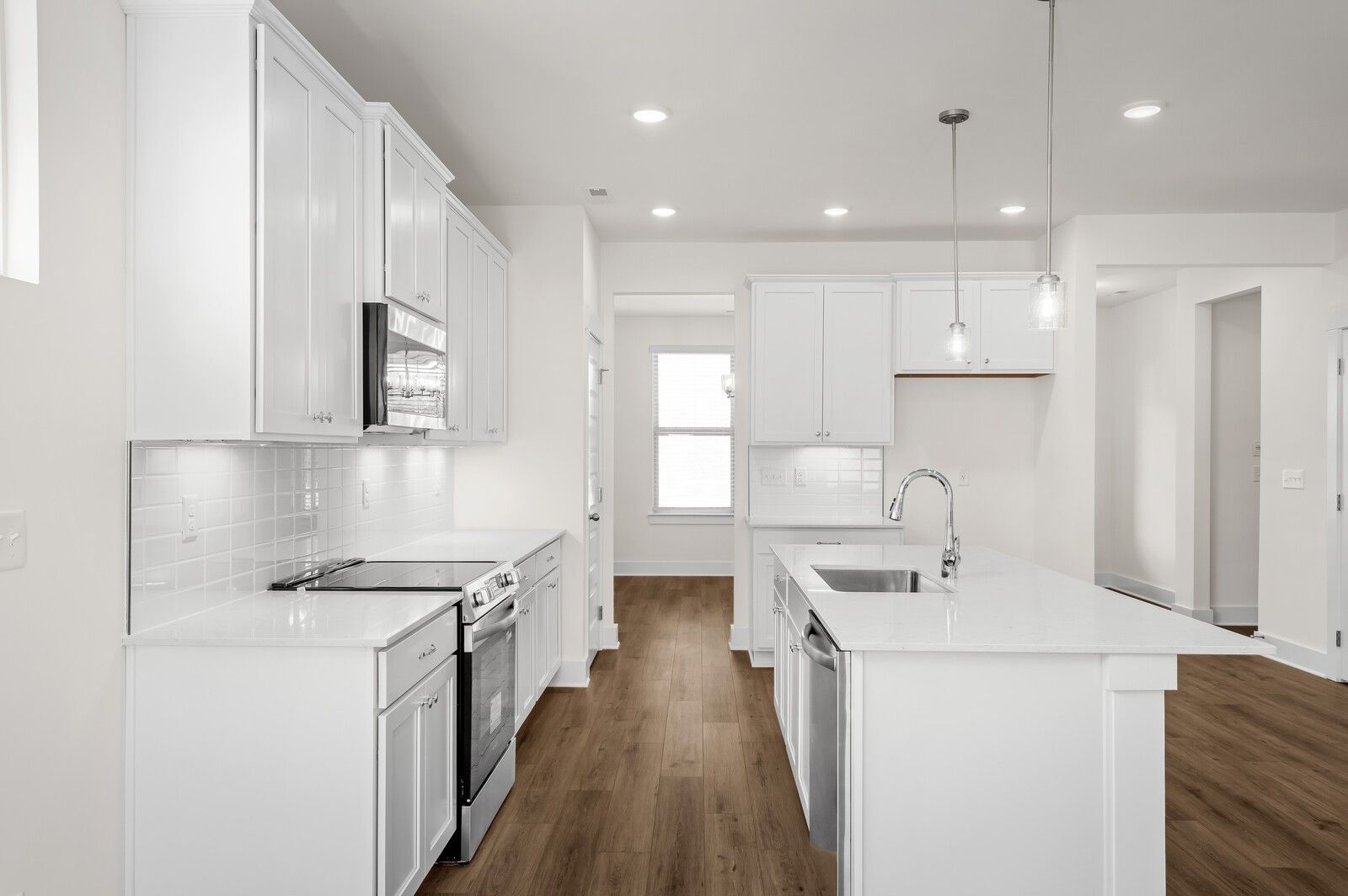 Modern kitchen with white cabinets, quartz countertops, and island in The Ash A floor plan at Woods Crossing, Gallatin, TN.